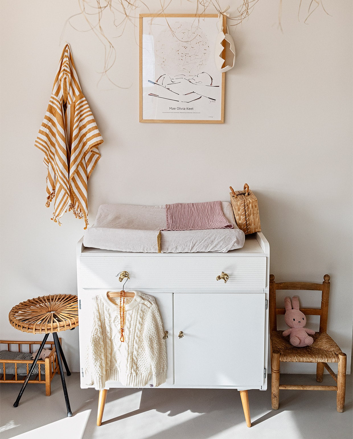 Muurverf Papyrus van Gamma, gietvloer Nature Grey. Hanglamp Couleur Locale, kunst aan muur MrStarsky, strandponcho kind Liewood. Vintage commode Marktplaats, deurknoppen Doing Goods. Poppenbed en kruk van Dirk van Sliedregt vintage. Kinderstoel erfstuk Roberts familie. Rieten koffer kringloop, juten kroon Suussies, naturel kroon en roze deken Archive Store. JA | vtwonen 13-2020 | styling Ilona Jongepier  | fotografie Dana van Leeuwen