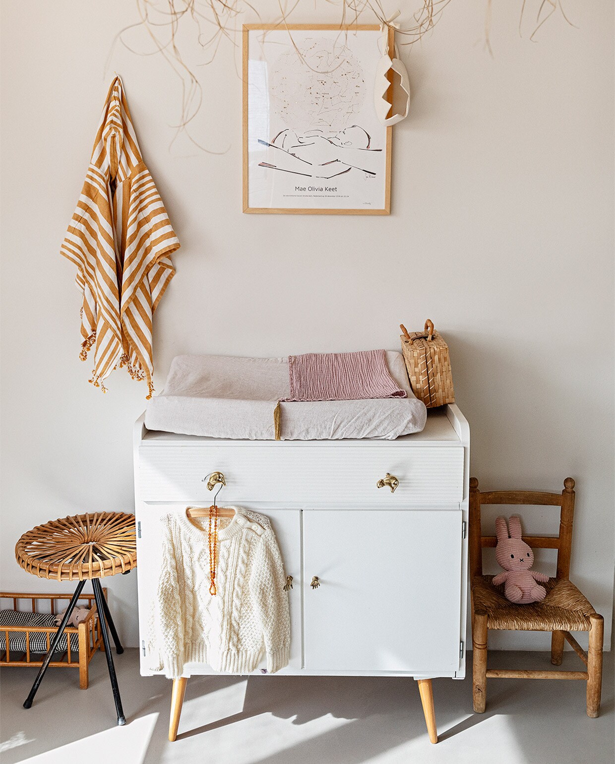 Muurverf Papyrus van Gamma, gietvloer Nature Grey. Hanglamp Couleur Locale, kunst aan muur MrStarsky, strandponcho kind Liewood. Vintage commode Marktplaats, deurknoppen Doing Goods. Poppenbed en kruk van Dirk van Sliedregt vintage. Kinderstoel erfstuk Roberts familie. Rieten koffer kringloop, juten kroon Suussies, naturel kroon en roze deken Archive Store. JA | vtwonen 13-2020 | styling Ilona Jongepier  | fotografie Dana van Leeuwen