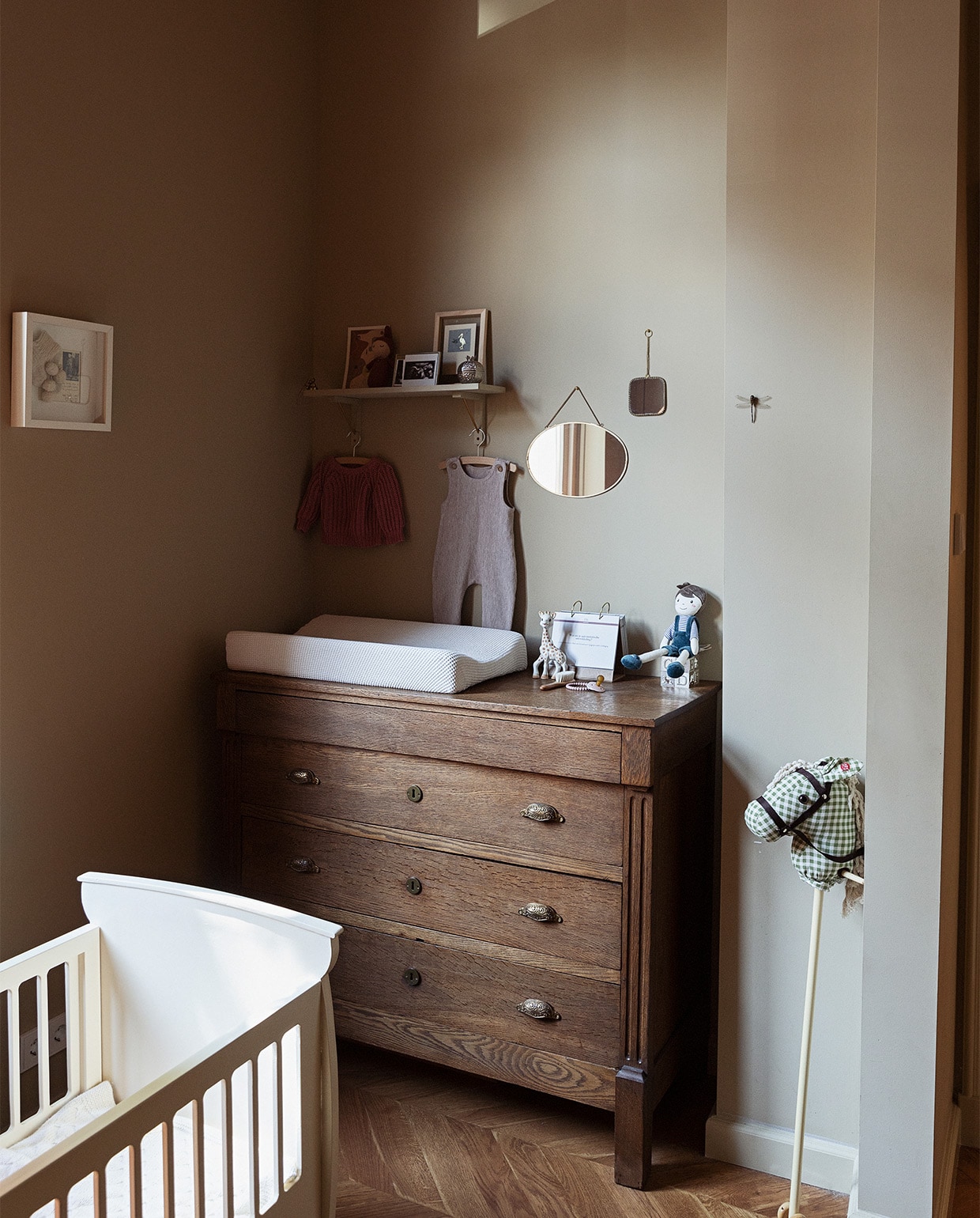 Doorgeefledikant van de familie van Louk. Commode Marktplaats. Stokpaard kraamcadeau van buren. Aankleedkussenhoes gemaakt door Lidians moeder. Spiegels De Weldaad. Wandplank Søstrene Grene. Kunstwerkje ooievaar Sjakie’s. Kunstwerkje Mia &amp;Wonder Studio. JA | vtwonen 08-2022 | styling Ilona Jongepier  | fotografie Dana van Leeuwen