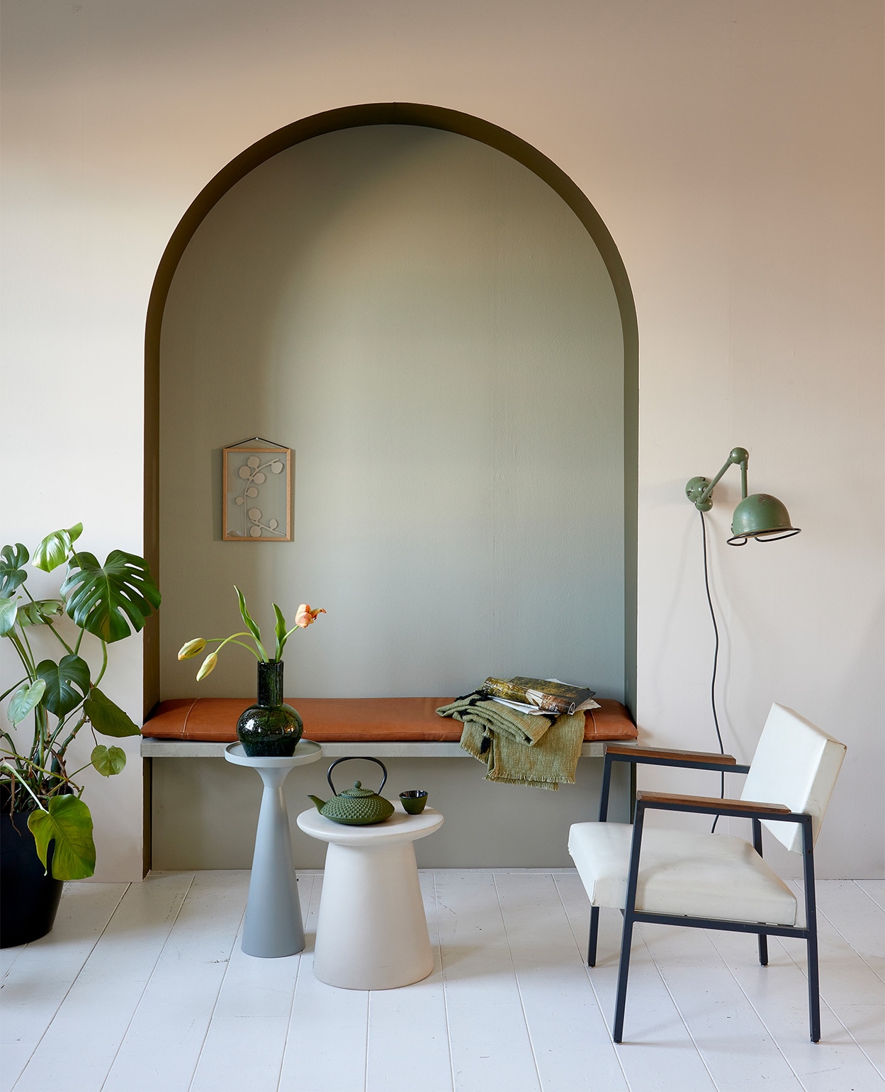 Muurverf krijtlook mat van vtwonen, kleur op de wand Linen, in boog Camouflage, op achterwand Stone, per liter € 14,20 (karwei.nl). Leren kussen op bank, 40x160x5 cm (bxlxh) € 339,- (nahka.nl). Vintage stoel met witte kunstleren bekleding € 175,-, Jieldé lamp aan de wand € 375,- (neeflouis.nl). Groene plaid, 130×170 cm € 74,95, aardewerken bijzettafel, 40×43 cm (Øxh) € 249,-, groene glazen vaas, 19×24 cm (Øxh) € 39,95 (hkliving.nl). Aluminium bijzettafel Floss, 28×56 (Øxh) € 110,- (zuiver.com). Gietijzeren theepot Xilin € 35,05 en gietijzeren kom Xilin van Bredemeijer, per 2 € 17,85 (vtwonen.nl). Aan de wand in nis: eikenhouten lijst Moebe, A4 € 44,- (nordicnest.nl). Overig privébezit. vtwonen 05-2022 | styling Fietje Bruijn | fotografie Dennis Brandsma