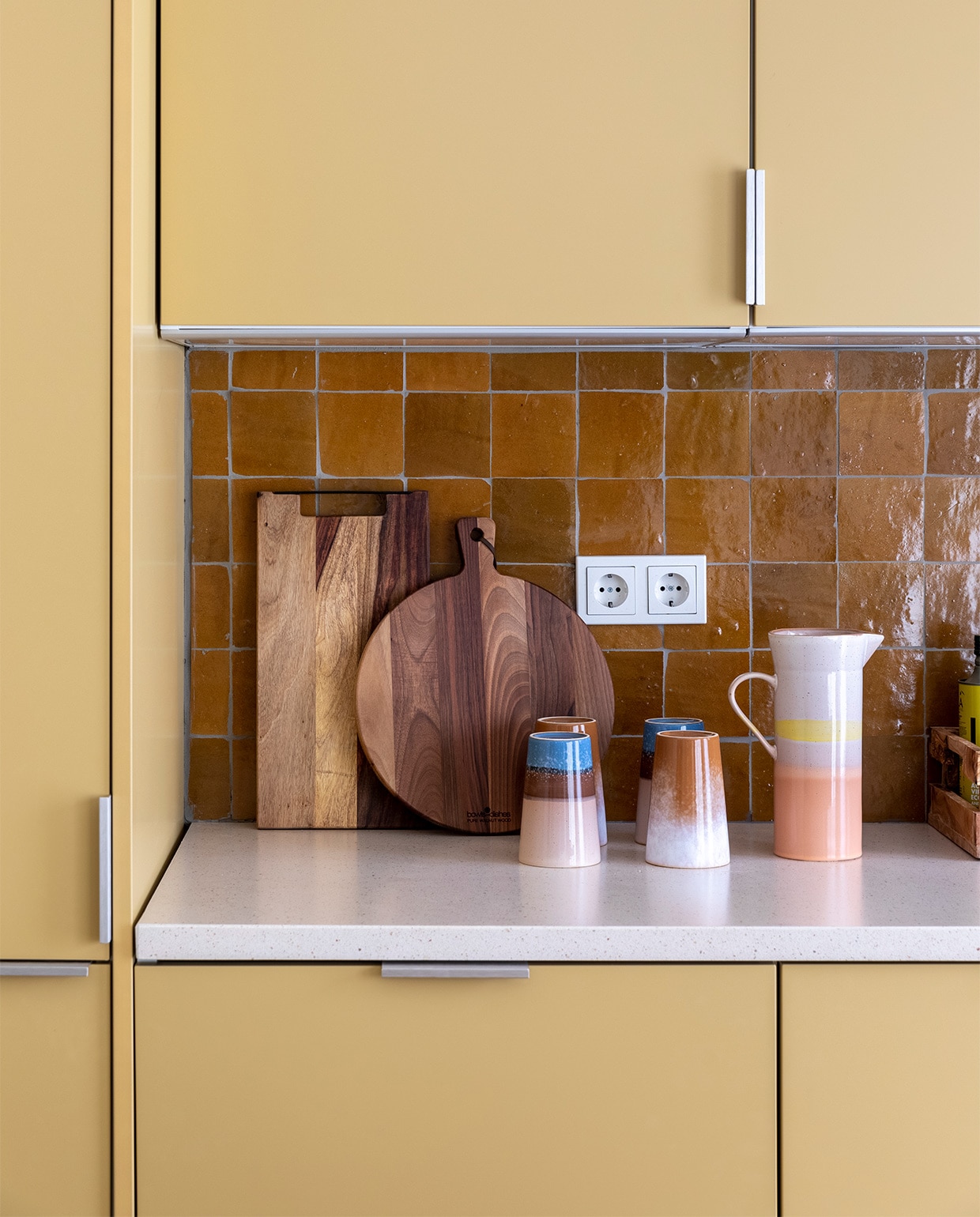 Flexa Creations muurverf om raam Midden Zandstrand (flexa.nl). Keukenkastfronten op maat gemaakt, prijs op aanvraag (k14.nl). Tegels achterwand Zelliges Mustard, per m² € 114,95 (householdhardware.nl). Houten planken van Bowls en Dishes vanaf € 15,-, koraalkleurige kandelaar van À la € 30,-, gele kandelaar Flare van Hay € 49,-, groene glazen vaas van Bloomingville € 38,90 (vtwonen.nl). Vijzel € 28,44 (bowls-dishes.nl). Kan € 29,95 en theemokken € 11,40 van HKliving (eijerkamp.nl). Kunstwerk Neutrale collage van Laura Horn € 50,- (werkaandemuur.nl). vtwonen weer verliefd op je huis extra seizoen 15, aflevering 3 | styling Marianne Luning | fotografie Margriet Hoekstra