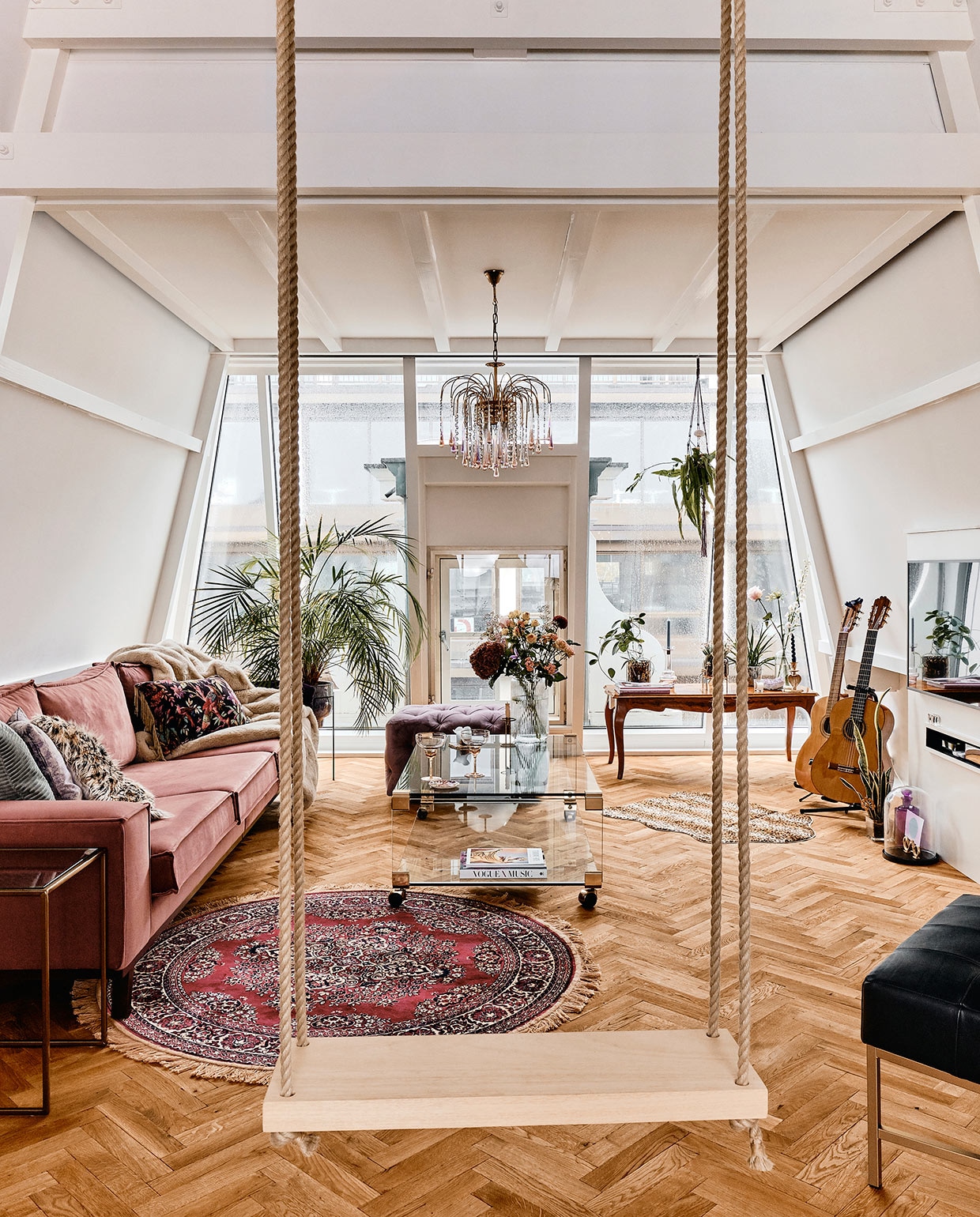 De schommel hing er al. Parket onbekend. Bank gekregen decorstuk voor een Louboutin fotoshoot. Vloerkleed, zwarte fauteuil, kussens op bank, vaas bij raam, kandelaar bij raam, plantenpotten, -standaards en pantervloerkleed Loods 5. Draaikaars Hay. Glazen salontafel Dig&amp;Dust Vintage. Poef en champagneglazen Homestock. Houten salontafel erfstuk oma. Bijzettafel en kandelaar Sissy-Boy. Kroonluchter Retro and More. Hangplant Flower Loves Me. Plaid Decor. Vaas Bloomon. Stolp met paars object gekregen. Tv-meubel gemaakt door vader. Tv Samsung The Frame. vtwonen 06-2021 | productie CocoFeatures | fotografie Roos Oosterbroek | tekst Anna van der Heijden