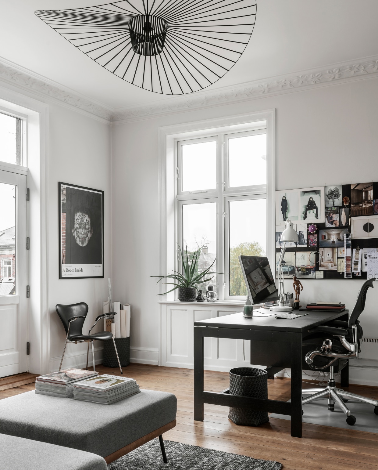 Daybed REM met bijpassende hocker van Sofacompany, Series 7 stoel door Arne Jacobsen, ingelijste poster met werk van fotograaf Trine Søndergaard, tweedehands bureau dat meerdere malen zwart is geverfd, bureaustoel ontworpen door Donald Chadwick en William Stump, plafondlamp Vertigo ontworpen door Constance Guisset, tweedehands bureaulamp Louis Poulsen. Moodboard met diverse knipsels, foto’s en kleurkaarten. vtwonen 11-2022 | productie Global Image | fotografie Peter Kragballen