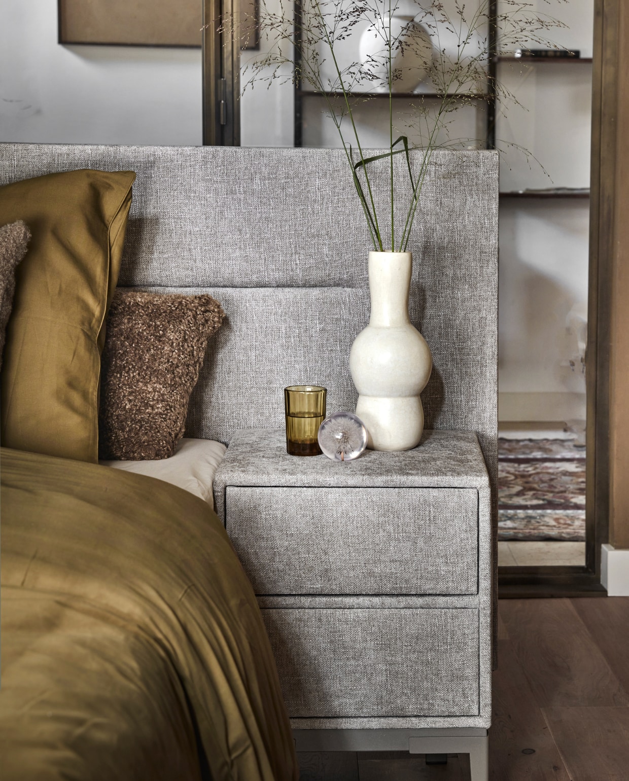 Boxspring Lifestyle by vtwonen Cinnamon Large in stof Mirage Taupe, vanaf € 2090,- (140×200 cm). Nachtkastje Cardemom met twee lades in stof Mirage Taupe met champagne frame en poot Track. vtwonen 12-2022 | productie Tanja Saarberg | styling Danielle Verheul | fotografie Peggy Janssen