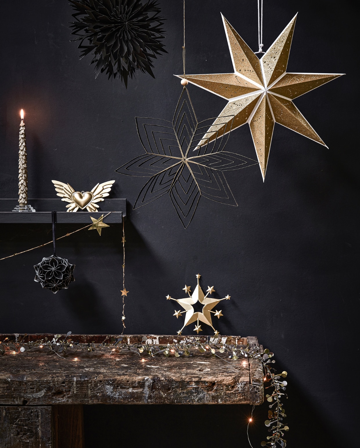 Zwarte papieren waaier, 30×7 cm (Øxd) € 3,99, zwarte papieren ster, 30×2 cm (Øxd) € 3,29 (ook verkrijgbaar in goud en wit), goudkleurige papieren ster, 70×19 cm (Øxd) € 9,99, goudkleurige kaars met glitter, per 2 € 6,99, goudkleurige metalen decoratie vleugels met hart, 18×10 cm (bxh) € 4,99, goudkleurige metalen slinger met sterren, 210 cm (l) € 3,49, zwart papieren ornament bloem met glitter, 10 cm (Ø) € 5,99, goudkleurige ster, 18×17 cm (hxb) € 7,29, goud- en zilverkleurige slinger met sterren en bolletjes, 120 cm (l) € 7,99. vtwonen 12-2022 | productie Tanja Saarberg, Isa Hoevens | styling Kim van Rossenberg | fotografie Peggy Janssen