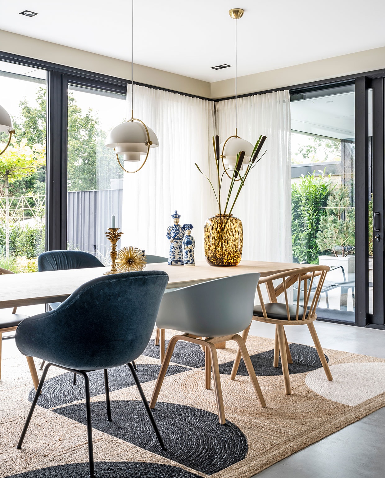 Hanglampen Multi-Lite Gubi, tafel Arp Design, vloerkleed Élitis, donker- en lichtblauwe stoelen Hay, houten stoelen zwarte zitting Bolia, gouden stekelitem Loods 5, kandelaar palmboom Anna+Nina, beelden Asian Mix Interior, vaas Artic Cheetah Vase the World, linnen gordijnen van Interstil. vtwonen 03-2021 | productie CocoFeatures | Styling Wendy Verhaegh | fotografie Stan Koolen