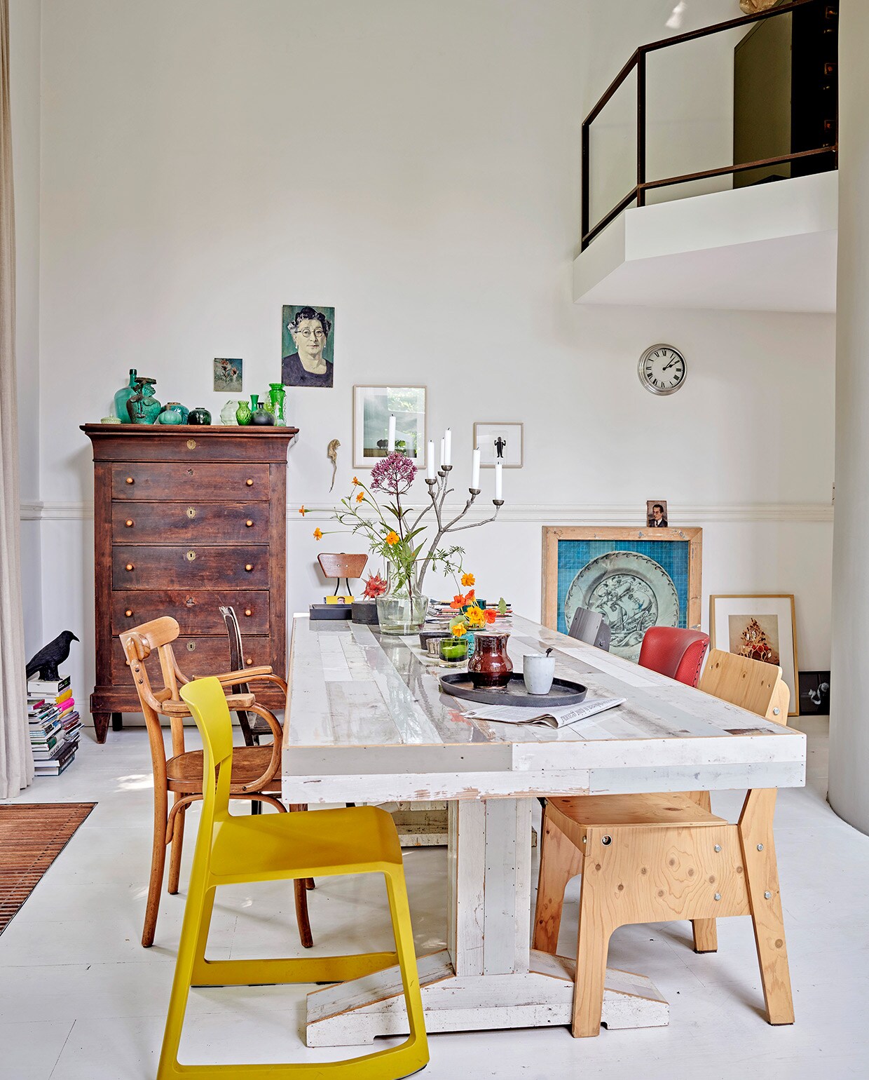 Oude grenenhouten vloer, wit geschilderd. Gele stoel Tip Ton van Vitra via Van Duivenboden. Eettafel Kantinetafel en stoel rechts voor Piet Hein Eek. Kandelaar Twiggy Large Sjakie’s. Kast Chiffonnière. Vogel raaf en dienblad Pols Potten. Kunst transfer op rijstpapier in houten lijst van Laurien Mulder. Papiermaché rat van Caroline de Bruijn. Vaas op tafel MrsBloom. Overig herkomst onbekend. vtwonen 07-2021 | productie Features &amp; More | styling Wilma Clusters | fotografie Renee Frinking \ntekst Chantal Hintze | tekstbewerking Laura Zuidema