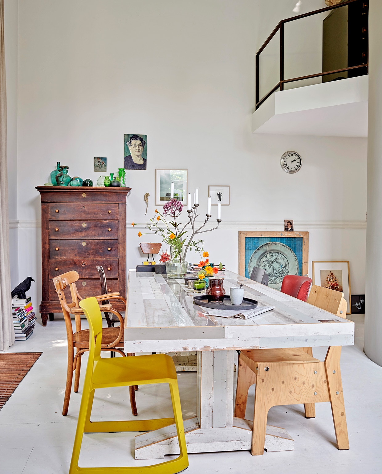 Oude grenenhouten vloer, wit geschilderd. Gele stoel Tip Ton van Vitra via Van Duivenboden. Eettafel Kantinetafel en stoel rechts voor Piet Hein Eek. Kandelaar Twiggy Large Sjakie’s. Kast Chiffonnière. Vogel raaf en dienblad Pols Potten. Kunst transfer op rijstpapier in houten lijst van Laurien Mulder. Papiermaché rat van Caroline de Bruijn. Vaas op tafel MrsBloom. Overig herkomst onbekend. vtwonen 07-2021 | productie Features &amp; More | styling Wilma Clusters | fotografie Renee Frinking \ntekst Chantal Hintze | tekstbewerking Laura Zuidema