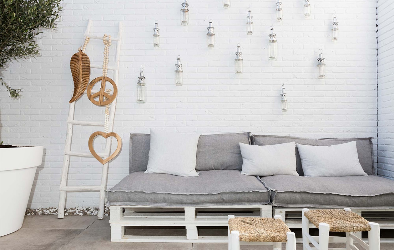 Tegels Solostone Hercules Grey uit de vtwonen buitentegelcollectie by Douglas &amp; Jones: vtwonen.nl. Kleur op de muur – Rijst 0601-G43Y: Histor Lampionnen: vtwonen.nl.Stoel: vtwonen.nl. Schaal zilver: Household Hardware. Olijfbomen: De Italiaanse Oase Potten ø80 cm: Elho Ladder: vtwonen.nl. Hangers madumad. Pallets: privébezit. Matraskussen en kussens: vtwonen.nl. Krukjes: Household Hardware Bijzettafel: vtwonen.nl. Servies: Household Hardware vtwonen weer verliefd op je huis | seizoen 9, aflevering 6 | styling Marianne Luning |  fotografie Barbara Kieboom