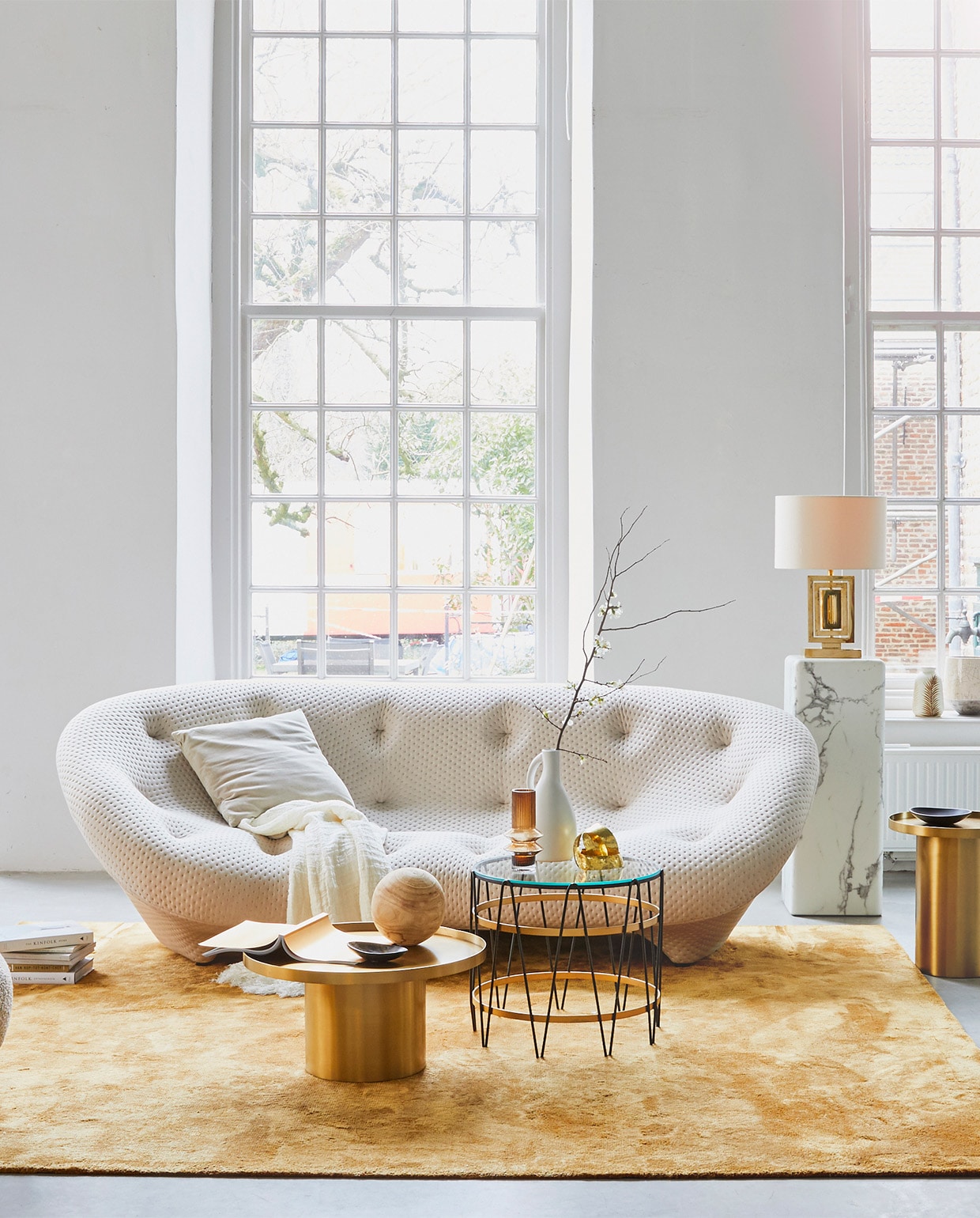 4-zitsbank Ploum van Ligne Roset, 124x84x253 cm (dxhxb) vanaf € 4633,-, okergeel vloerkleed Soft van Jov 260×300 cm € 2738,-, messing bijzettafels, 60×31 cm (Øxh) € 598,-, 43×47 cm (Øxh) € 548,- (misterdesign.nl). Bijzettafel met glas en metaal, Ø 50 cm € 550,-, lamp van messing met zijden kap € 750,- (paullelieveld.com). Marmeren pilaar, 33x33x91,4 cm (lxbxh) € 425,-, voetenbankje Pebble € 150,- (polspotten.nl). Linnen plaid € 275,-, okergele vaas € 18,20 (nordal.eu). Grijs fluwelen kussen € 26,50, vaas bladdessin € 27,- (madamstoltz.dk). Zwarte kommen € 25,- (vtwonen.nl). Overig privébezit. vtwonen 02-2019 | styling Cleo Scheulderman | fotografie Jeroen van der Spek