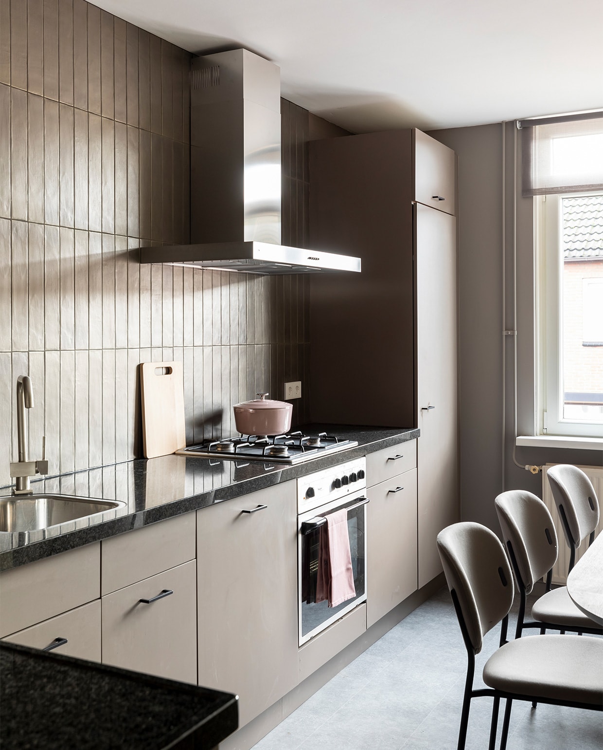 Flexa Creations muurverf bij de ramen Authentic Grey, Flexa Creations lak voor de keukenfronten Sweet Umber (flexa.nl). Wandtegels Marrakesh Bronze mat van vtwonen by Douglas &amp; Jones (douglasjones.nl). Zwarte grepen, per stuk € 3,59 (karwei.nl). Eetkamerstoelen Yo, per stuk € 277,50 (eijerkamp.nl). Wandklok € 165,- (zuiver.com). Braadpan van BK € 79,- (fonq.nl). Vaas van vtwonen € 44,95 (vtwonen.nl). Overig privébezit. JA | vtwonen extra aflevering weer verliefd op je huis 6 | styling Fietje Bruijn | fotografie Margriet Hoekstra