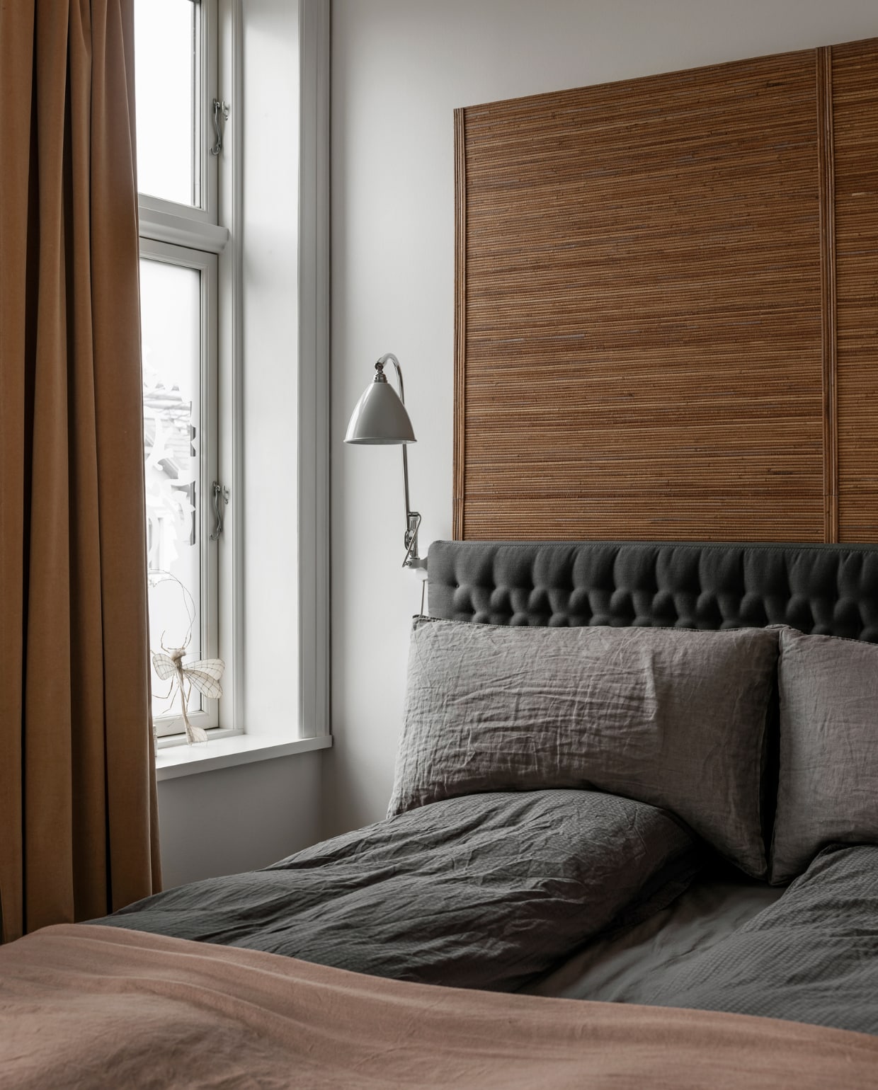 Bed met grijse headboard Dux, bedlinnen Facet ontworpen door Line’s moeder voor Georg Jensen Damask, gordijnen en caramelkleurige achterwand bed zelfgemaakt, witte lamp Bestlight. vtwonen 11-2022 | Productie Global Image | Fotografie Peter Kragballen
