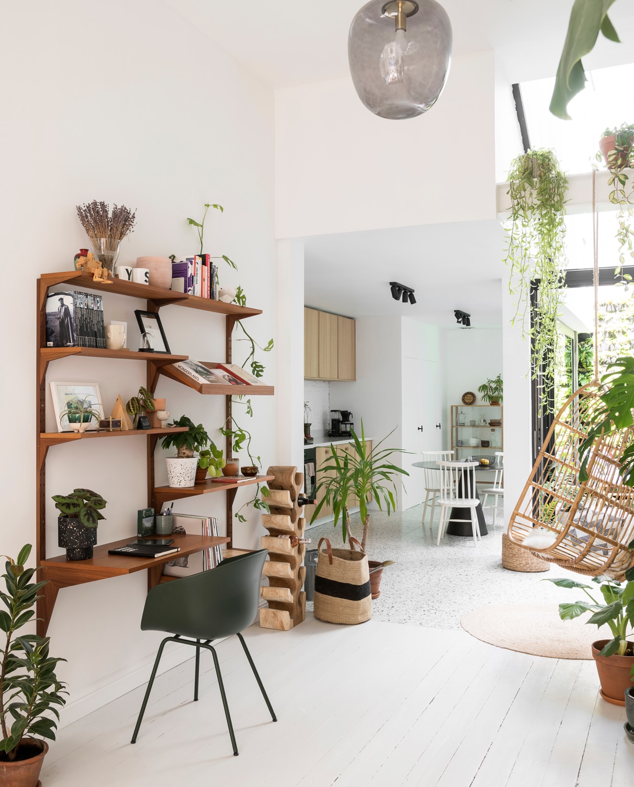 De draagbalk werd bewust niet weggewerkt zodat plantenpotten er een plaatsje konden krijgen. Het mid-century wandmeubel is van Nome Furniture, de bureaustoel van Hay, de hangstoel van Casa en het ronde tapijt van House Doctor. De rotan poef is van Casa. vtwonen 13-2019 | styling &amp; fotografie Jonah Samyn | tekst Katrien Depoorter