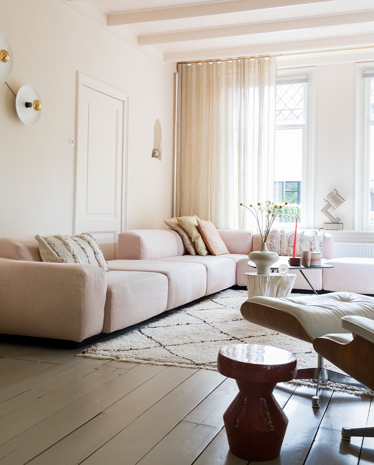 Bank Soft modular van Jasper Morrison en stoel Eames via Vitra. Vloerkleed en kussens links en rechts Household Hardware. Kussens midden Blooming Interior. Witte bijzettafel en vaas van Pols Potten via Wim van Assem bloembinderij. Zwarte bijzettafel Leolux en bijzettafel voorgrond via Eijerkamp.Wanden, deur, plafond kleur Julie_s Dream van Little Greene. Vloer kleur Brown Wood van Vestingh Paint. Papier-mach_ lamp Tradition via Loods 5. Gordijnen Van den Bosch Interieurstoffen. Messing railroede Corpus van Interstil. Presse papier Hafod Grange. Wandlampen vtwonen. Theebeker en koektrommel HKliving. Onderzetters Ikea. Kaars Ester &amp; Erik. vtwonen 02-2022 | styling Ilona Jongepier | fotografie Dana van Leeuwen
