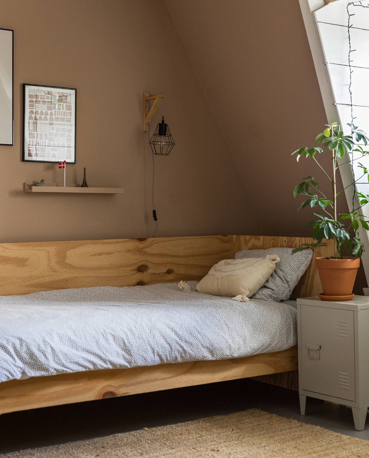 Muurkleur GN-087-07. Bed zelfgemaakt. Beddengoed, sierkussen Hema. Lamp, nachtkastje Kwantum. Vloerkleed, wandplank Ikea. Print van Silvia Visscher. Plant via Nørd Conceptstore. vtwonen 10-2022 | styling Ilona Jongepier | fotografie Dana van Leeuwen