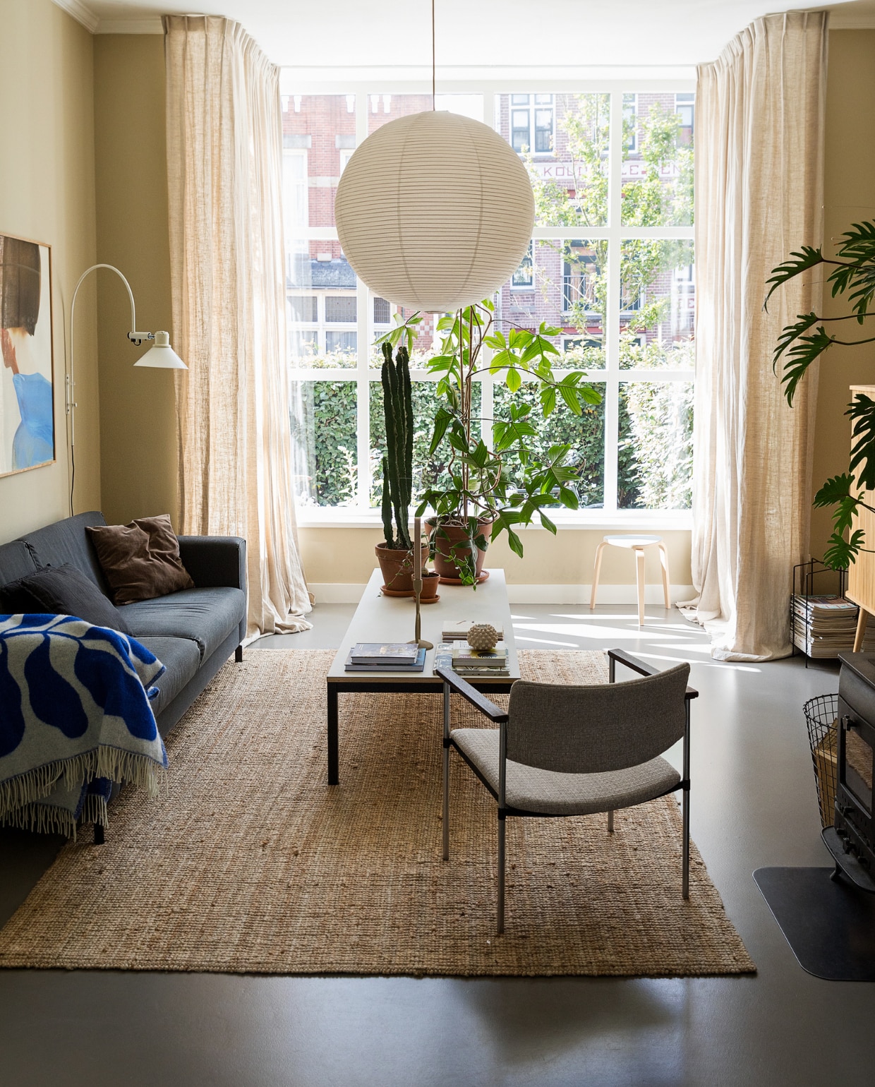 Muurkleur GN 080-08. Hanglamp Hay. Bank onbekend. Stoel Kembo via vintagemarket12. Salontafel zelfgemaakt. Plaid van Linnea Andersson voor Arket. Wandlamp vintage. Tijdschriftenrek Designtorget. Vloerkleed Ikea. Kruk Trinity Furniture. Print van Amelie Hegardt, boeken, planten via Nørd Conceptstore. Notitieboeken Monk & Anna. Kandelaar Broste Copenhagen. Waxinelichthouder Jotex. vtwonen 10-2022 | styling Ilona Jongepier | fotografie Dana van Leeuwen