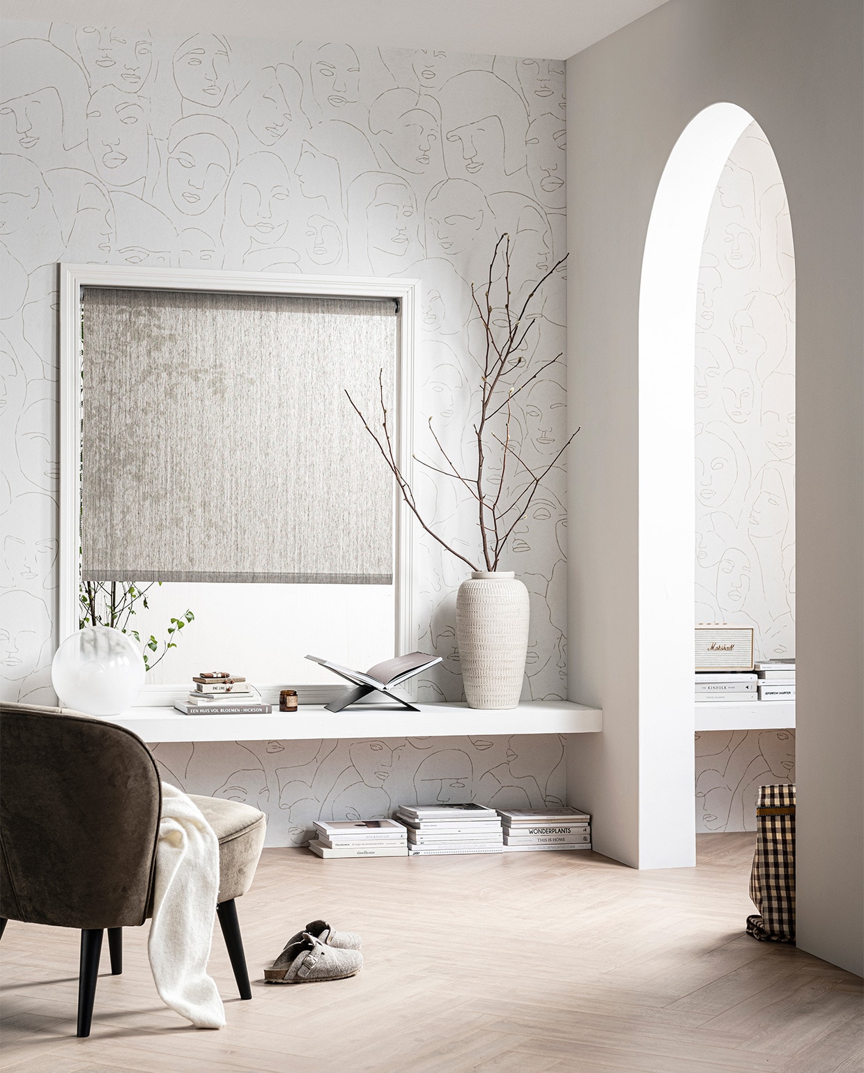 Fotobehang Faces, 3 banen van 280×50 cm, totaal 280×150 cm (hxb) € 99,-, laminaat XL visgraat Rafter naturel, inhoud per pak 1,24 m² € 29,99, verf op de muur en de boog Egg White, 1 liter € 18,95, 2,5 liter € 32,95 (mengmachine) , rolgordijn Typhoon 150×190 cm (bxh) € 97,99 (ook verkrijgbaar in breedtematen 60, 90, 120, 180 en 210 cm). M.m.v. karwei.nl (fauteuil Sarah Rib Honing , tafellamp, glas), mendo.nl (boekenstandaard). Overig privébezit. JA | vtwonen 08-2020 | styling Kim van Rossenberg  | fotografie Sjoerd Eickmans | productie Tanja Saarberg
