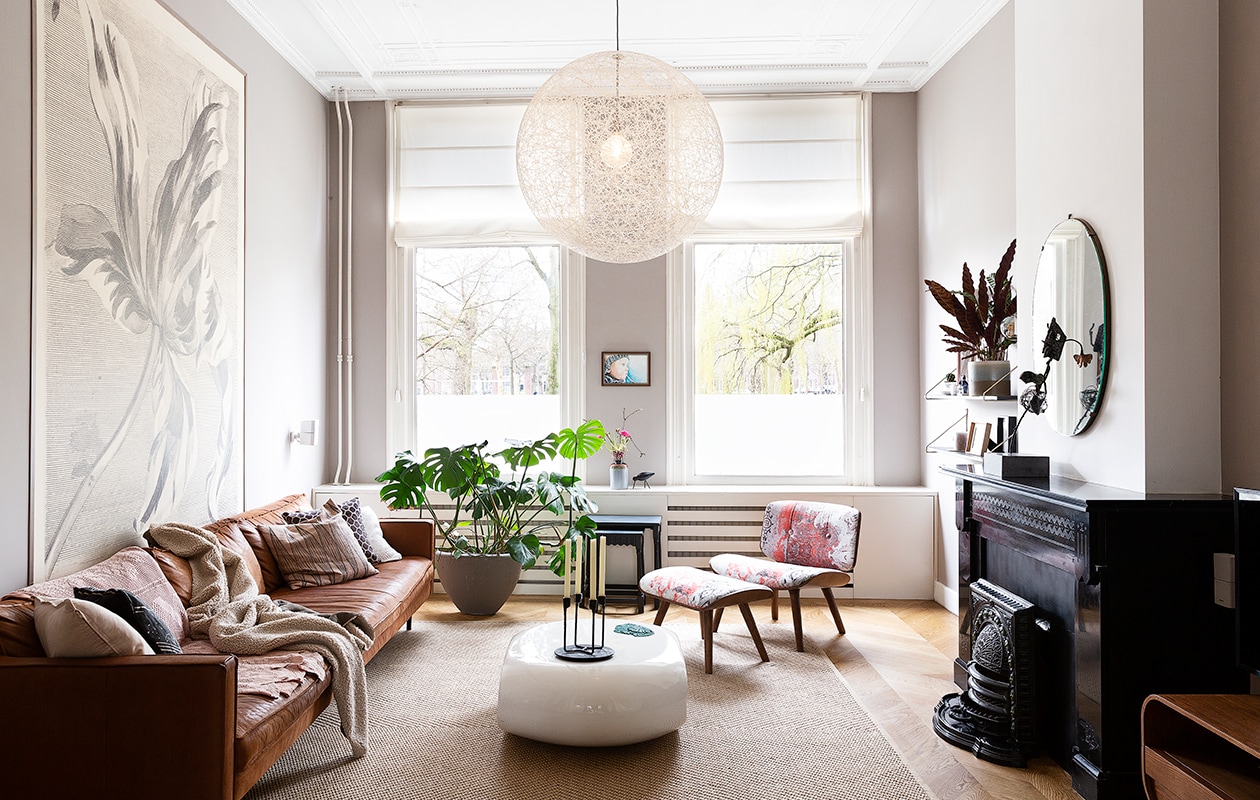 Behang Eijffinger. Bank Loods 5. Kussens Loods 5, Zuiver en Ikea. Plaid gemaakt door Merijns oma. Salontafel in België gekocht. Vaas Bloomingville. Kandelaar Normann Copenhagen. Voetenbank en lamp Moooi. Bloempot Flow Rotterdam. Vloerkleed Ikea. De tafeltjes waren van Stans oma. Portret gemaakt door Merijns oom. vtwonen 04-2020 | styling Emmy van Dantzig | fotografie Jansje Klazinga