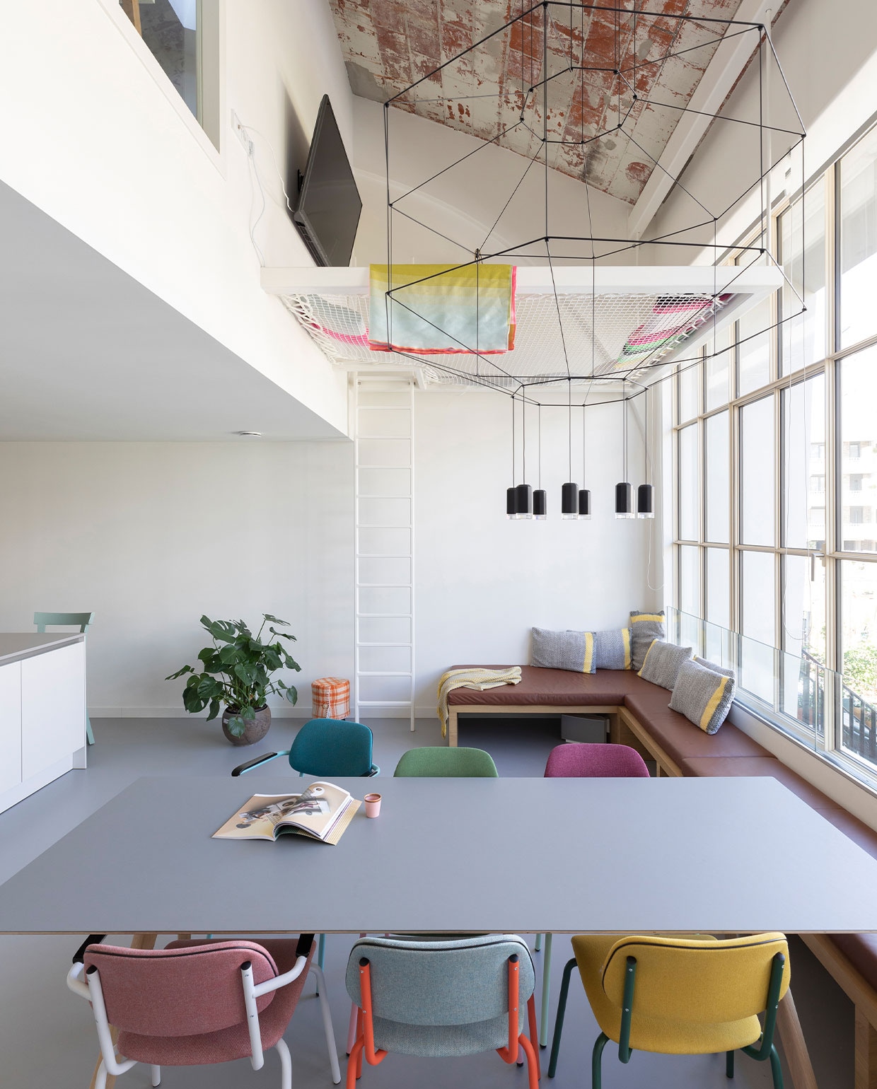 Hangnet Loftnets op maat gemaakt, frame en ladder laten maken door ingenieursbureau Onderwaater. Eettafel CPH30 van Hay, eetstoelen Lande Jami van Artifort, lamp boven eettafel Wireflow van Vibia. Gietvloer Bruizt. Raambank op maat gemaakt door Combo Design. Plaid op hangnet Hay. Kussens Colour Cushions van Hay. vtwonen 03-2022 | fotografie Margriet Hoekstra