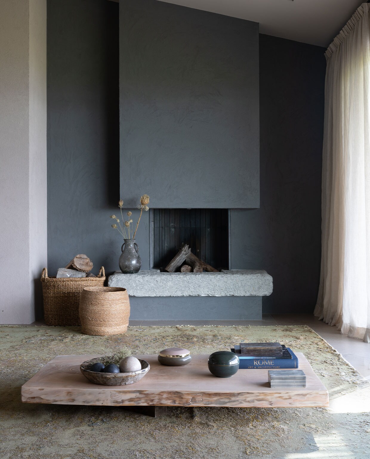 Lavastenen open haard ontworpen door Hanne Poli. Manden House Doctor. Antiek vloerkleed Tisca. Tafelblad gevonden op een schroothoop. Kommen meegenomen van reizen. Overig onbekend. vtwonen 07-2023 | productie Living Inside | fotografie Monica Spezia