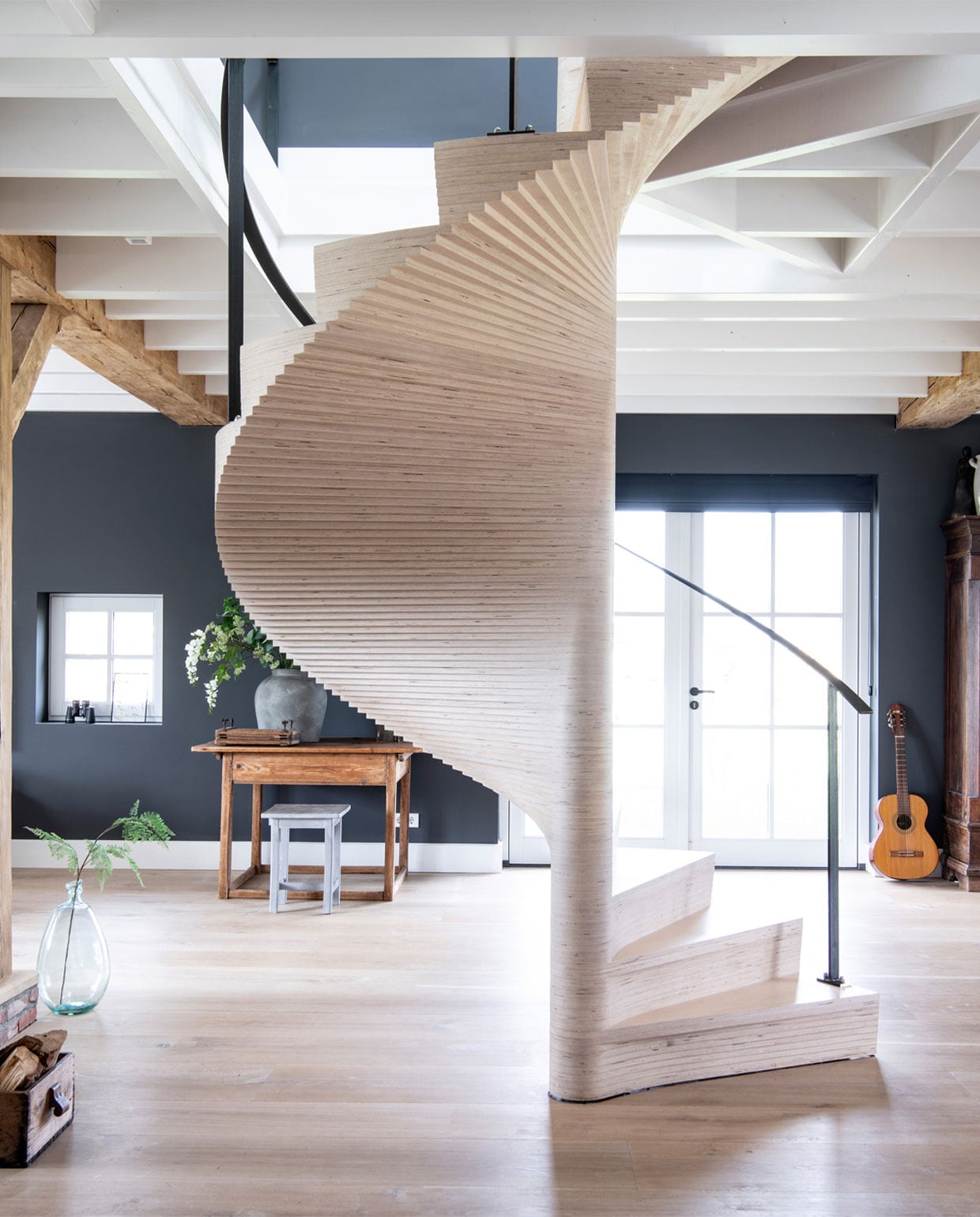 &gt; Licht eiken plankenvloer in drie breedtesDennebos Flooring, trap ontworpen door Buro Loggein samenwerking met Westenwolf Trappen.Balkenconstructie oude onbehandelde eiken balkenFrank Pouwer, vazen Tica, verf op de muur PersianGrey van Painting the Past. Bijzettafel, aardewerkpotten, kist met houtblokken rommelmarkt, gitaarResonata, kruk Stapelgoed, kast antiekwinkel. vtwonen 13-2020 | Productie Insidehomepage | Styling Marlies Does | Fotografie Louis Lemaire | Tekst Cathelijne van Wingerden