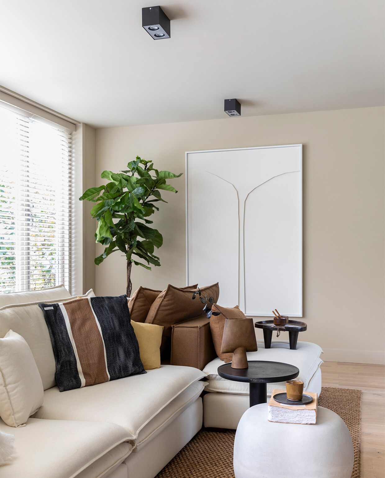 Flexa Creations muurverf en lak plinten en kozijnen F4.10.70, muurverf plafond F6.08.75 (flexa.nl). Houten Luxaflex op maat gemaakt (woninginrichting-aanhuis.nl). Kastenwand houtdecor S158 Okobo van Decolegno op maat gemaakt (meijermaatinterieurs.nl). Groot wit kunstwerk Papercut prijs op aanvraag (theheritageseries.nl). Vloerkleed 3797 Safari prijs op aanvraag (cunera.nl). Elementenbank Pien vanaf € 3299,- (eijerkamp.nl), kussens in kleuren Honey, Wheat en Cinnamon, per stuk € 59,-, plaid € 99,- (bymolle.com). Gestreept kussen Yoko € 39,95 (mlfabrics.nl). Fauteuil Elephant van Norr11 € 1999,-, bruine bijzettafel Place van BePureHome € 119,-, vloerlamp van DCW Editions € 980,-, vaas op bijzettafel Square van 101 Copenhagen € 50,-, vaas in vensterbank van Eurofashion € 139,95. Droogtakken en planten prijs op aanvraag (waterdrinker.nl). Dienblad op bank € 125,- (o-live.nl). Televisie Crystal UHD 50 inch TU7020 € 499,- (samsung.com). Betonlook bijzettafel Pebble € 129,- (basiclabel.nl). Keramieken poef € 250,- (angeliquehomberg.nl). Houten lepel vanaf € 5,50 (hkliving.nl). Kandelaar Abstract van Bloomingville € 26,90, bord Pure € 10,45, bruine kop van Serax € 10,85, houten kop van Serax € 12,60, plafondlampen van Philips, per stuk € 62,15 (vtwonen.nl). In de tv-kast plantenmand ontworpen door Marie Michielssen prijs op aanvraag, ornament vogel van Vitra € 90,-, marmeren steen van Eurofashion € 41,95, bruine vaas met oren € 17,99 (eijerkamp.nl), steen op voet van Wide Stoney € 91,95, kaart prijs op aanvraag (sukha.com), marmeren blok € 39,95 (stonedmarble.com), zwart bakje € 12,99 (hm.com). Vloer zie foto 1, overig privébezit vtwonen weer verliefd op je huis | seizoen 13, aflevering 10 | styling Liza Wassenaar | fotografie Margriet Hoekstra