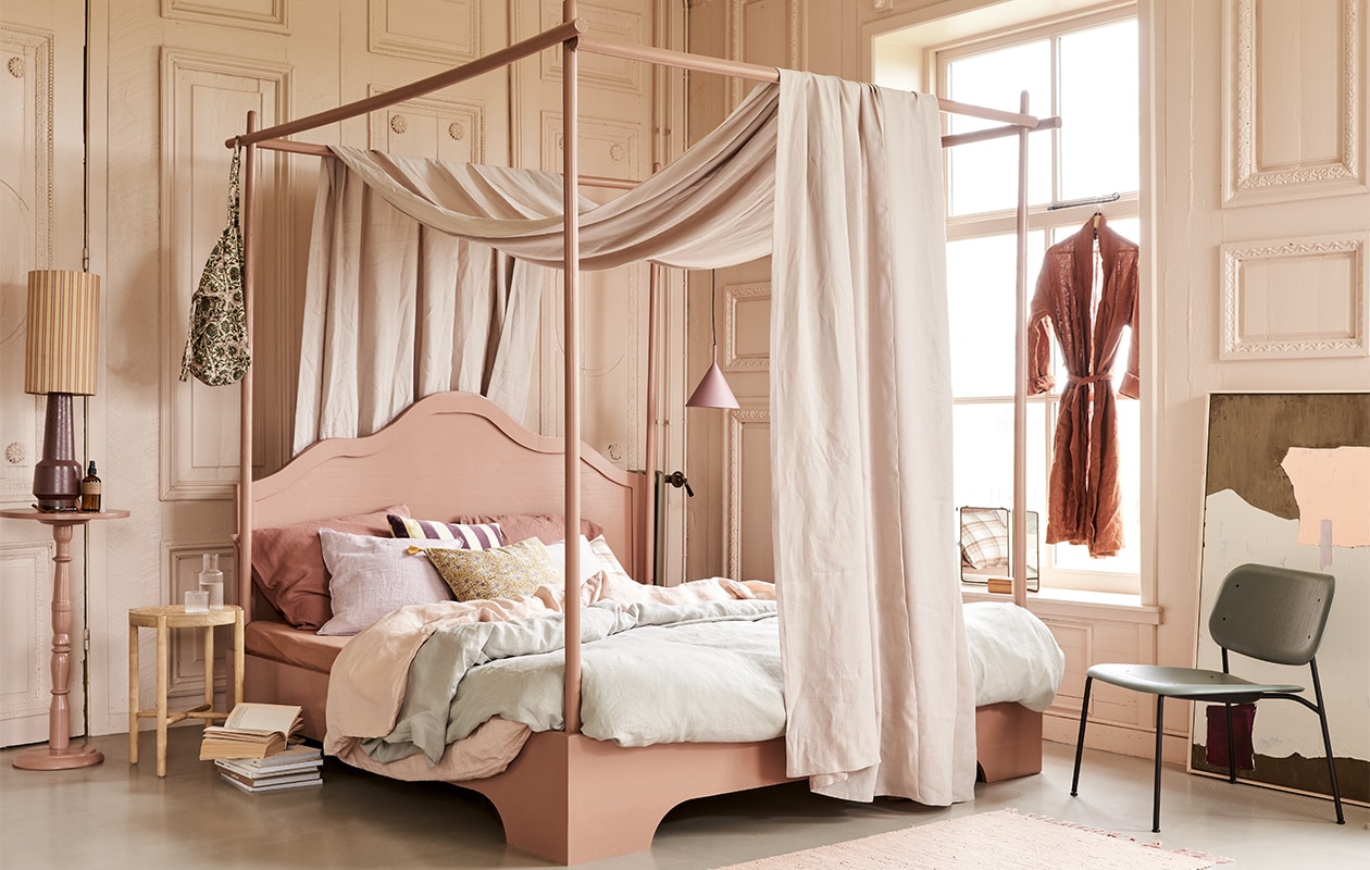 Bed, op maat gemaakt en geschilderd in kleur 86DI64 van D’Imago,180×210 cm prijs op aanvraag, tafeltje op hoge voet geschilderd in kleur 86DI64 van D’Imago, 75 cm (h) € 45,- (com-anders.nl). Hemel Glenmoye van linnen in kleur Nougat van Designers Guild, per meter € 62,- (wva.nl). Dekbedovertrekset van gewassen linnen in kleur Misty Green, 240×220 cm € 319,-, dekbedovertrekset in Dusty Rose, 240×220 cm € 319,-, kussenslopen in Clay Rose, 50×60 cm € 39,95 (yumeko.nl). Lampenkap Doris van HKliving € 49,95, lampvoet € 159,-, artwork, 100×120 cm € 549,-, hanglamp mat paars € 95,-, velvet kussen met paars-gele strepen € 34,95, houten krukje met webbing zitting € 129,- (hkliving.nl). Tas met print € 40,-, linnen kussen Lilac Rose € 45,-, kussen met bloemenprint in geel Lily Masala € 47,-, roze vloerkleed Chindi Mat Rose, 60×90 cm € 20,- (scandicliving.nl). Kussen met ruitprint € 49,90, roomspray € 29,90, karaf met glas van Ferm Living € 35,90 (letoile.store). Spiegel € 49,- (jolandelijkdewebshop.nl). Fauteuil in groen Soft Edge 10 € 269,- (vtwonen.nl). JA | vtwonen 05-2021 | styling Marlies Does | fotografie Bart Brussee
