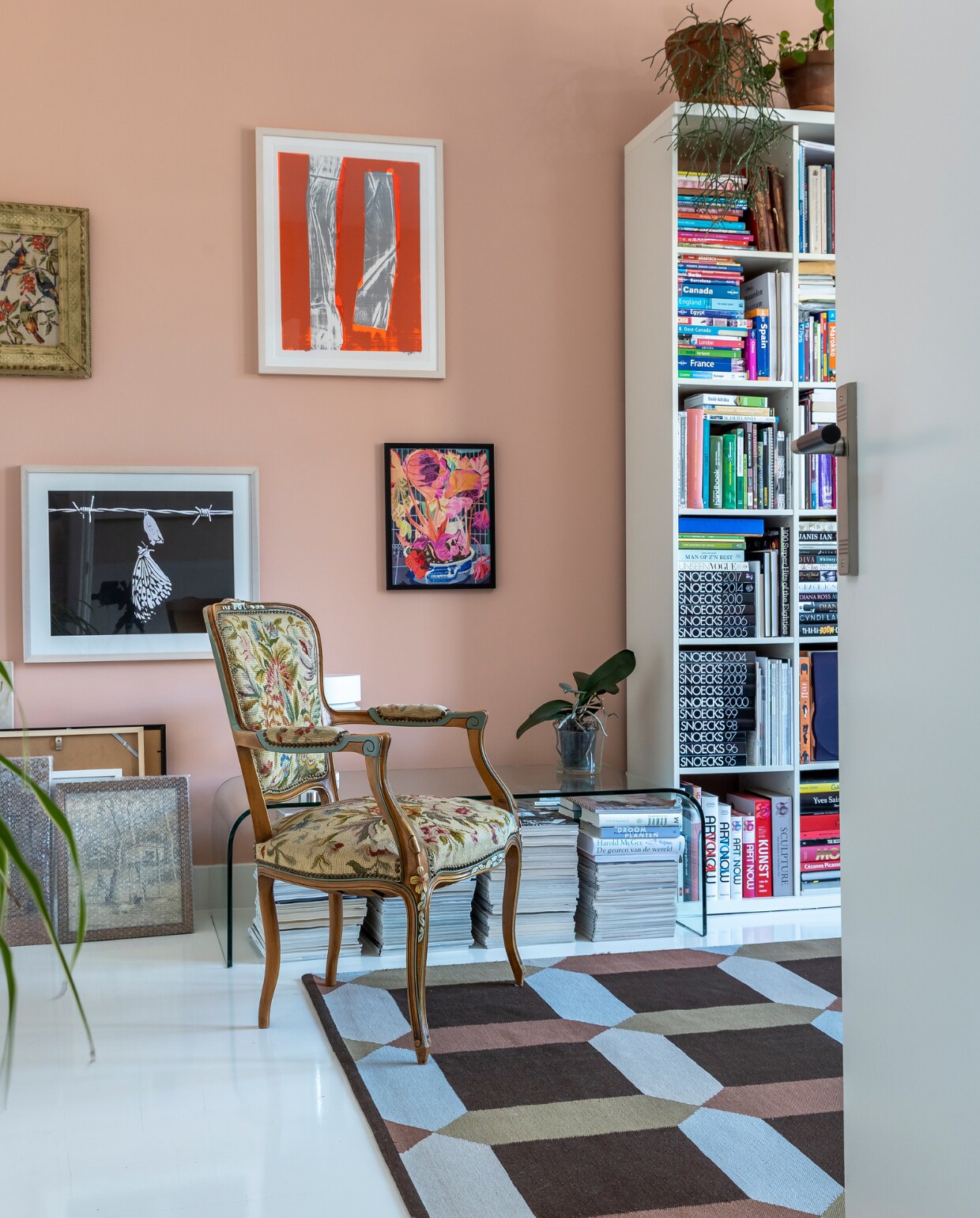 Muurverf Farrow &amp; Ball, kleurnaam onbekend. Kunst aan de muur v.l.n.r. Birgit Verwer, Marjan Laaper, Jochem Rotteveel, Johan Kleinjan, herkomst vintage stoel onbekend, glazen salontafel Murano. Kleed en boekenkast Ikea. Vloer witte epoxylak over oud parket. vtwonen 10-2022 | fotografie Henny van Belkom