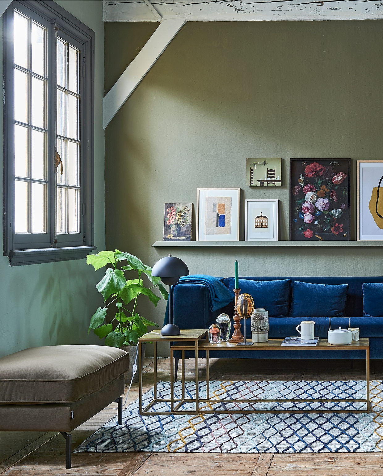 Op de wand muurverf Classico in kleur Tundra (pure-original.com). Bank van blauw velvet , lampje op salontafel (loods5.nl). Salontafel brass, stoel met houten frame, grote blauwe vaas, poef, geborduurd kussen op de bank (polspotten.nl). Zwarte metalen bijzettafel, retro vaas, glazen kwallen, namaak schildpad, theepot (hkliving.nl). Kom, kan, rozenbotteltak XL (weldaad.com). Vloerkleed (ikea.nl). Op de wandlijst: v.l.n.r. schilderij met bloemen (privébezit), grafisch werk (hkliving.nl), illustratie gemeentehuis van Michiel van der Zanden, 30×20 cm (sbk.nl), erboven stoel + tafel (privébezit), print bloemen van het Rijksmuseum (rijksmuseum.nl/nl/rijksstudio), in lijst Hovsta (ikea.nl), grafisch werk (loods5.nl), bloemenschilderij (privébezit). Goudkleurige oude spiegel(decamer.nl). vtwonen 01-2019 | styling Fietje Bruijn | fotografie Dennis Brandsma