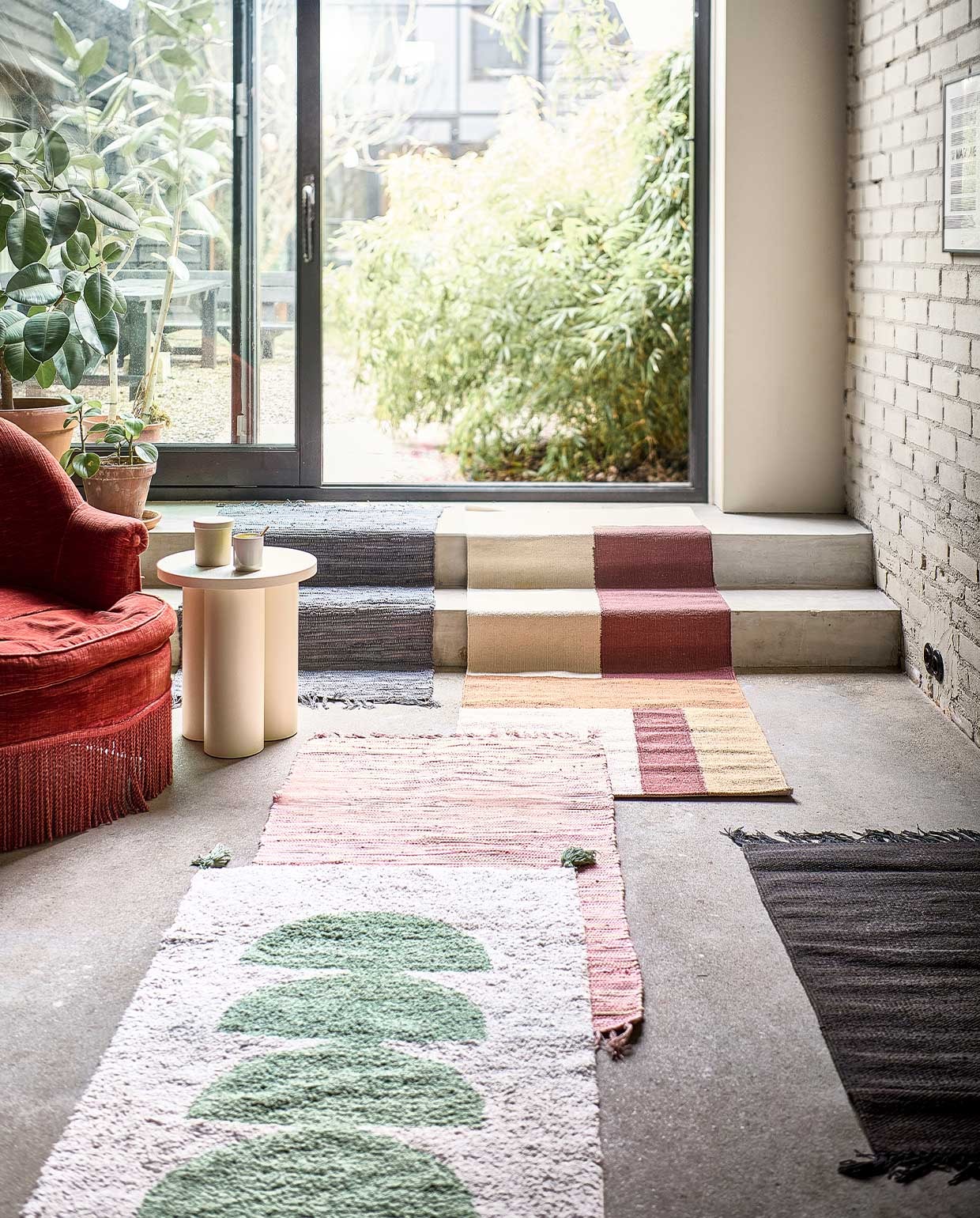 Roze en lichtgrijze vloerkleden Chindi van Bungalow, 60×90 cm per stuk € 15,-, donkerbruin vloerkleed van Ferm Living, 60×100 cm € 29,25, multicolour, handgeweven vloerkleed 70×200 cm € 107,50 (deens.nl). Kruk Oly van Noo.Ma in kleur Piazza Beige € 289,- (vtwonen.nl). Terracotta bloempotten en schotels in verschillende maten, vanaf € 6,95 (intratuin.nl). Groen-witte katoenen loper met kwastjes van Madam Stoltz, 70×140 cm € 71,75 (deens.nl). vtwonen 04-2022 | Styling Marlies Does | Fotografie Sjoerd Eickmans | Assistentie Yara Wagner