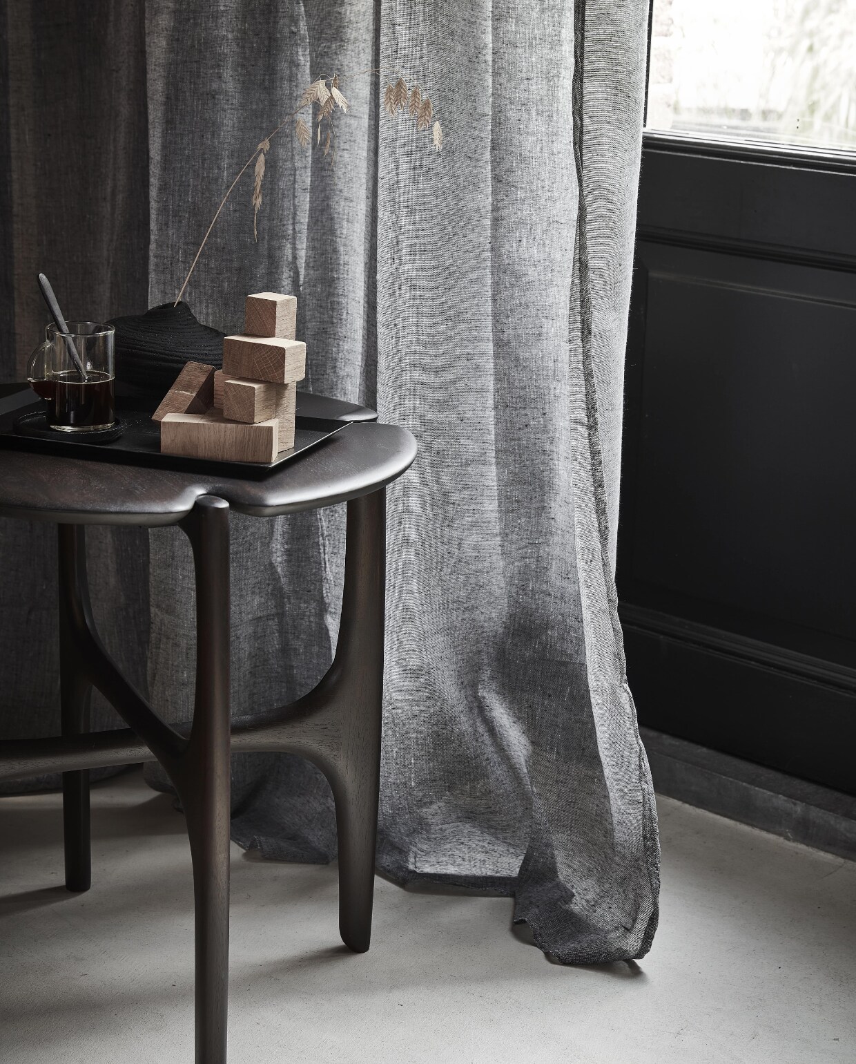 Grijs gordijn Frost, half transparant, met plooi, 270×140 cm (hxb) € 44,99M.m.v. vanbinnen.com (bijzettafel), zarahome.com (houten blokspel, metalen dienblad, espressokopje), hm.com/home (zwart vaasje). Overig privébezit. NEE | vtwonen 11-2022 | Productie Tanja Saarberg | Styling Sanne Ketelaar | Fotografie Peggy Janssen