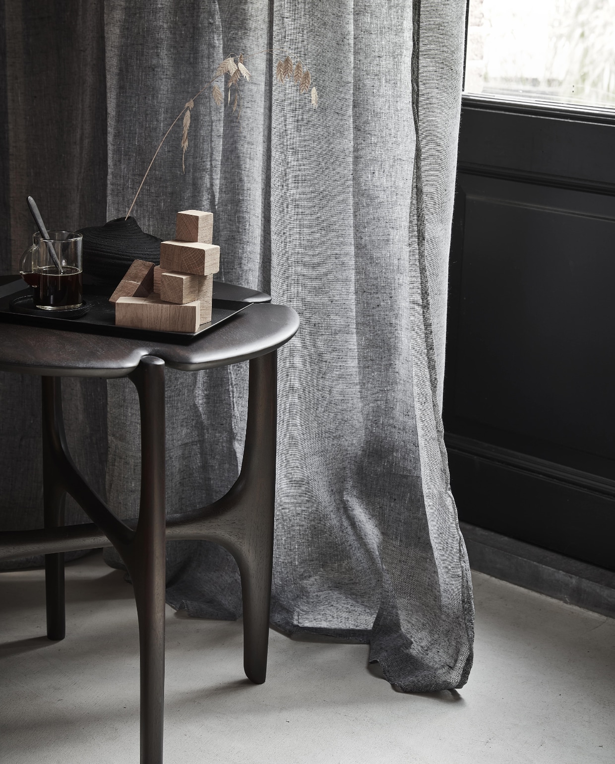 Grijs gordijn Frost, half transparant, met plooi, 270×140 cm (hxb) € 44,99M.m.v. vanbinnen.com (bijzettafel), zarahome.com (houten blokspel, metalen dienblad, espressokopje), hm.com/home (zwart vaasje). Overig privébezit. NEE | vtwonen 11-2022 | Productie Tanja Saarberg | Styling Sanne Ketelaar | Fotografie Peggy Janssen