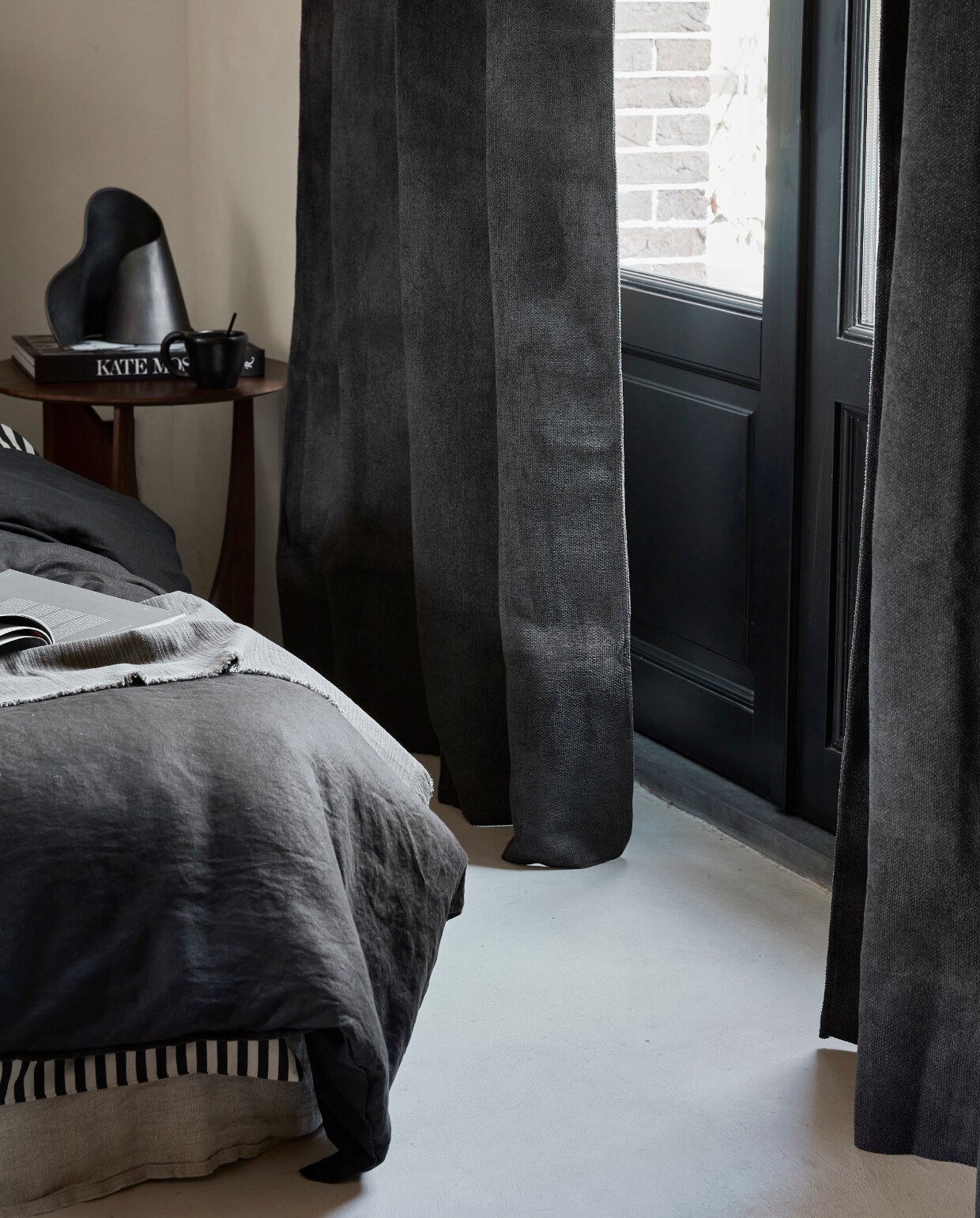 Antraciet gordijn Snow, verduisterend, met plooi, 270×140 cm (hxb) € 64,99M.m.v vanbinnen.com (bijzettafel), hm.com/home (linnen dekbedovertrek, dekbedovertrek met streep), zarahome.com (linnen onderlaken), homestede.nl (metalen organische tafellamp). Overig privébezit. NEE | vtwonen 11-2022 | Productie Tanja Saarberg | Styling Sanne Ketelaar | Fotografie Peggy Janssen