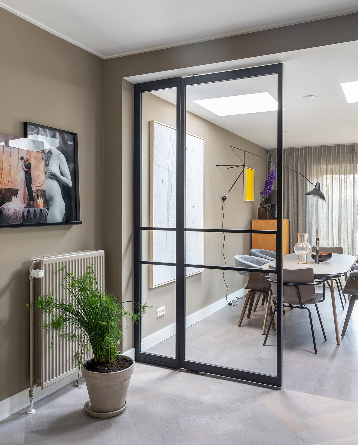 Aluminium tussenwand met deuren prijs op aanvraag (gewoongers.nl). Flexa Creations muurverf in de eetkamer Brave Ground, in de keuken Worthy Clay (flexa.nl). Massief eikenhouten visgraatvloer, licht gerookt en afgewerkt met olie prijs op aanvraag, betonlook pvc vloer prijs op aanvraag (woninginrichting- aanhuis.nl). Transparante gordijnen Jetze prijs op aanvraag (eijffinger.com). Aluminium deuren prijs op aanvraag (gewoongers.nl). Oven, kookplaat prijs op aanvraag (atag.nl). Tafel Tree van Woud € 1199,-, grijze stoelen Catch van BePureHome, per stuk € 159,-, bruine stoelen Patch van Bodilson, per stuk € 239,-, zwarte wandlamp Mantis € 950,- (eijerkamp.nl). Groot wit kunstwerk naast tafel Brutalism € 595,-, felgeel kunstwerk € 195,- (hkliving.nl). Hanglamp Marlon € 78,99 (zuiver.com). Tafellamp op de wandplank in de keuken Athens € 73,- (itsaboutromi.nl). Vaas van HKliving € 39,95, zwarte kandelaars per stuk vanaf € 15,25 (vtwonen.nl). Overig privébezit. JA | vtwonen weer verliefd op je huis | seizoen 13, aflevering 8 | styling Fietje Bruijn | fotografie Margriet Hoekstra