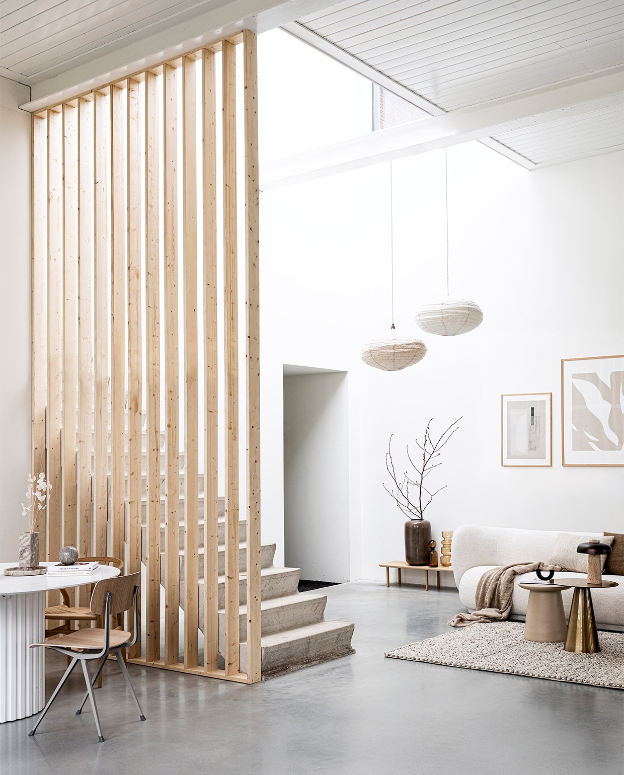 Scheidingswand gemaakt van latten uit vtwonen DIY 09-2020. Laag houten wandmeubel Loof Piled, 24x150x35 cm (hxbxd) € 275,-, zwarte kandelaar Arch van Ferm Living € 45,99 (vtwonen.nl). Marmeren bol € 29,99, bouclé plaid 130×170 cm € 14,99 (hm.com). Grote vaas Jade achter trap € 99,95, bruine glazen vazen achter trap vanaf € 32,95, linnen kussens 40×40 cm € 39,95 en 40×60 cm € 45,- (loods5.nl). Wollen vloerkleed Hjorthede, 160×230 cm € 299,- (ikea.nl). Messing bijzettafel 49×49 cm (Øxh) € 239,-, aardewerken bijzettafel 40×43 cm (Øxh) € 195,- (hkliving.nl). Bouclé 3-zitsbank Rico van Ferm Living, 210x79x81,5 cm (bxhxd) € 3389,- (flinders.nl). Posters: groot Fragments van Moe Made It, 70×100 cm met eikenhouten lijst € 109,- klein Carrarra van Julia Hallström Hjort, 50×70 cm € 89,- met eikenhouten lijst € 69,- (theposterclub.com). Boeken privébezit. vtwonen special 09-2020 | styling Kim van Rossenberg | fotografie Sjoerd Eickmans