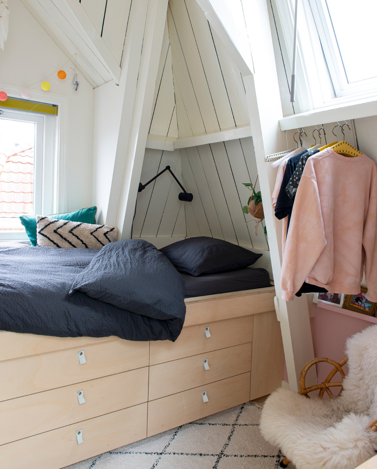 Zigzag kussen van HKliving, het bed heeft een basis van Ikea met zelfgemaakte fronten en leren handgreepjes, schapenvacht Polspotten, rotan stoel vintage, wandlamp Ikea, vloerkleed Søstrene Grene, blauw kussen Raaf, beddengoed Hema, lichtsnoer onbekend. vtwonen 10-2022 | productie De Binnenkijkers | styling Jeske Weel | fotografie Caroline Coehorst