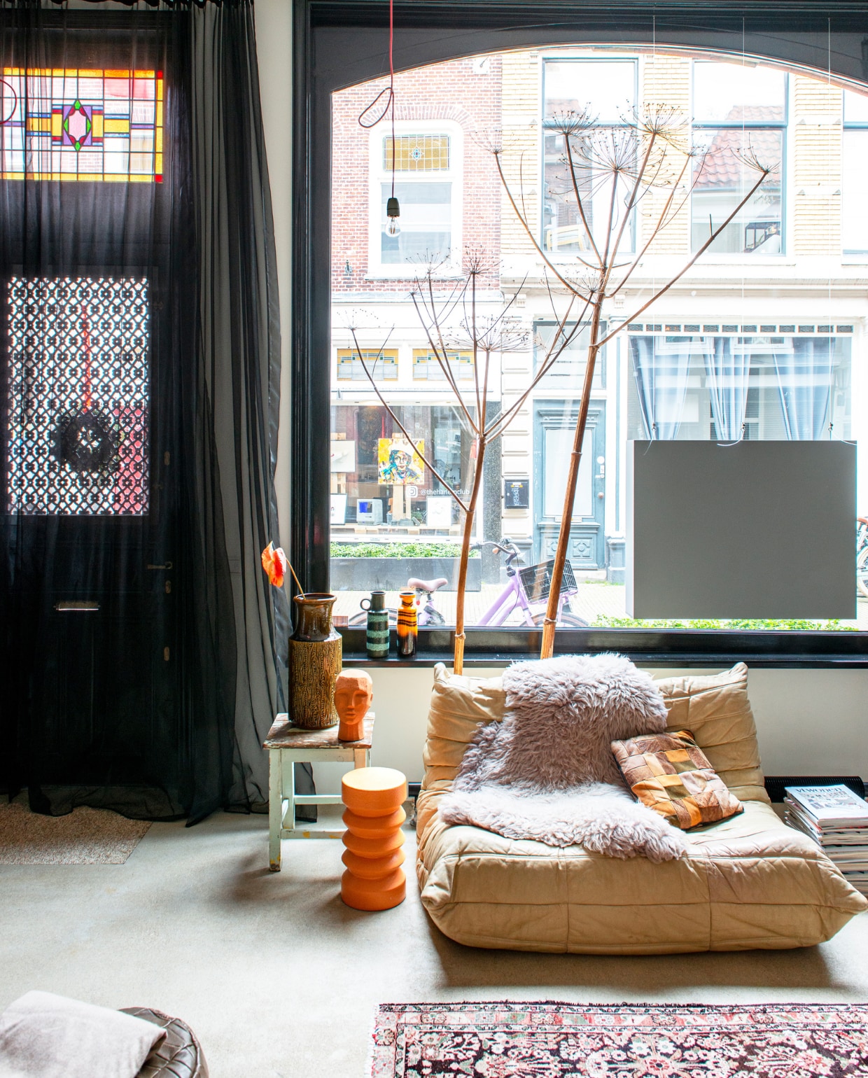 Oranje kruk en hoofd HKliving, houten kruk De Handelsfabriek, vintage fauteuil Togo van Ligne Roset via Marktplaats, schapenvacht Pols Potten, patchwork kussen rommelmarkt, vintage West-Germany-vazen via Sprinkel + Hop, stof deurgordijn en spankabel Ikea, hanglamp zelfgemaakt met materiaal van Sjakie’s, Perzisch tapijt kringloopwinkel. vtwonen 10-2022 | productie De Binnenkijkers | styling Jeske Weel | fotografie Caroline Coehorst