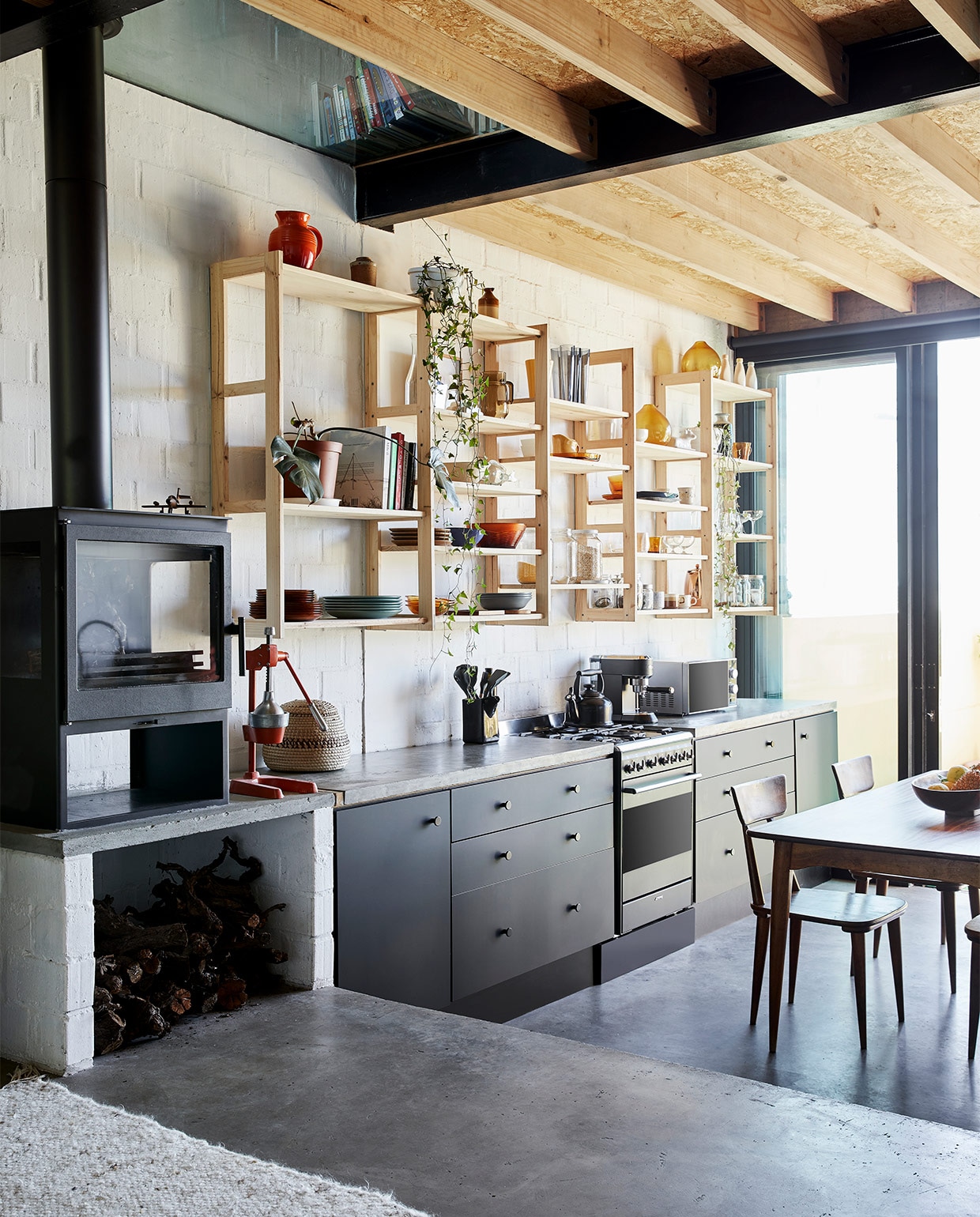 Houtkachel Calore, hangkasten zelfgemaakt, fornuis Smeg. Tafel en stoelen familiestukken. Keuken zelfontworpen. NEE | vtwonen special binnenkijken maart 2022 | productie Bureaux | fotografie Warren Heath | styling Sven Alberding