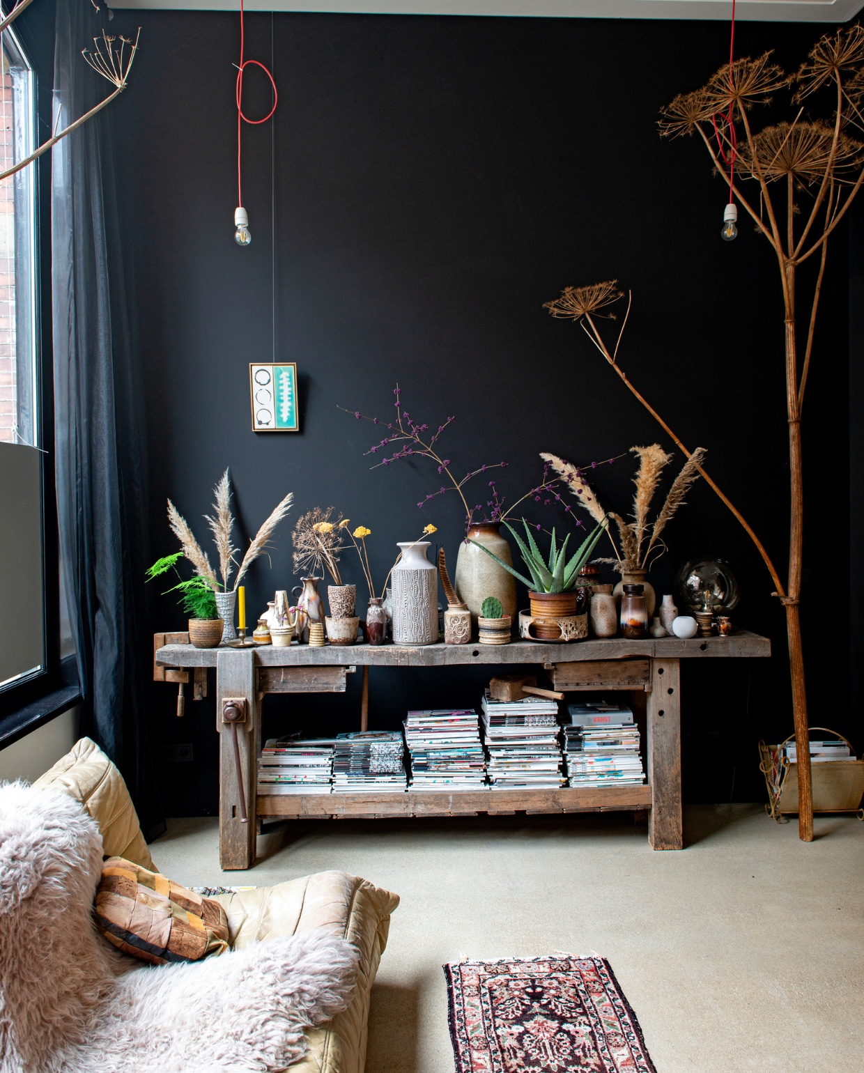 Kunstwerk Rollmann Ceramics, schapenvacht Pols Potten, vintage Togo van Ligne Roset, vintage vazen o.a. van Sprinkel + Hop, Perzisch tapijt vintage, patchwork kussen van rommelmarkt, werkbank en tijdschriftenrek van brocantemarkt in Frankrijk, berenklauw zelf geplukt, snoerlampen zelfgemaakt met materiaal van Sjakie’s, zandcement dekvloer met epoxy coating. vtwonen 10-2022 | productie De Binnenkijkers | styling Jeske Weel | fotografie Caroline Coehorst