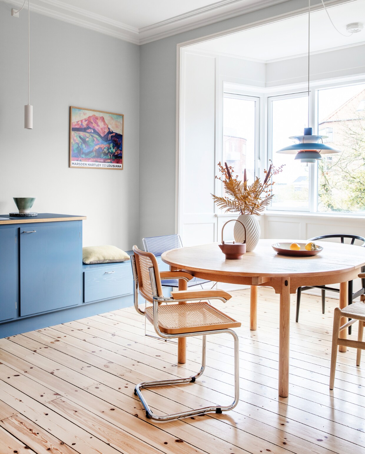 Muurverf Morgendis van Jotun. Keuken Stilleben Architects. Peper- en zoutstel Hay. Tafel Øresund van Børge Mogensen. Vaas Morsø. Theepot Skagerrak og Stilleben. Stoelen Hans Wegner, Niels Jørgen Haugesen en Marcel Breuer. Originele houten vloer, gerestaureerd. Witte hanglamp Light-Point. Blauwe hanglamp PH 5 van Poul Henningsen. Kussen Hay. Overig herkomst onbekend. vtwonen 09-2022 | productie Living Inside | styling Rikke Graff Juel | fotografie Christina Kayser O.