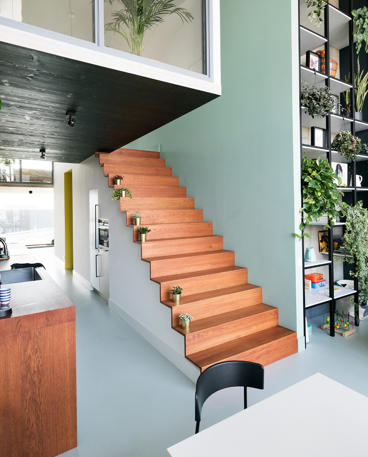 Maatwerkkeuken, eikenhouten trap en stalen kast ontwerp Martijn Frank Dirks, uitvoering Spinder Interieurbouw. Vloer DGF polyurethaan PU Gietvloer in kleur NO.05.65 via Design Gietvloer Amsterdam. Gouden bloempotten Ikea. Grijze verf Sikkens ACC Aqua Zijdeglans kleur SN.02.57. NEE | vtwonen 09-2022 | styling Emmy van Dantzig | fotografie Jansje Klazinga | tekst Martine de Hoog