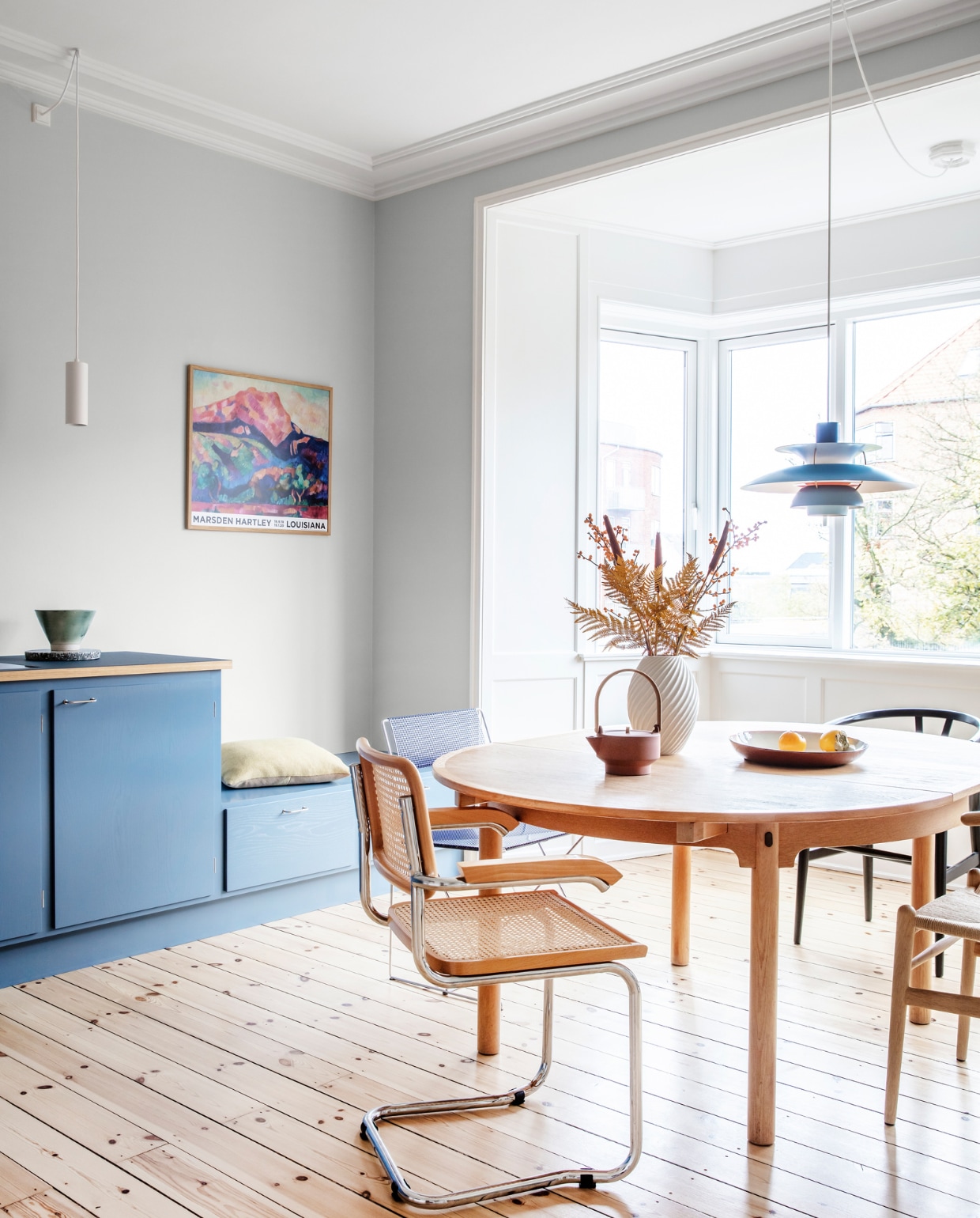 Muurverf Morgendis van Jotun. Keuken Stilleben Architects. Peper-en-zoutstel Hay. Tafel Øresund van Børge Mogensen. Vaas Morsø. Theepot Skagerrak og Stilleben. Stoelen Hans Wegner, Niels Jørgen Haugesen en Marcel Breuer. Originele houten vloer, gerestaureerd. Witte hanglamp Light-Point. Blauwe hanglamp PH 5 van Poul Henningsen. Kussen Hay. Overig herkomst onbekend. NEE | vtwonen 09 2022 | binnenkijken | productie Living Inside | styling Rikke Graff Juel | fotografie Christina Kayser
