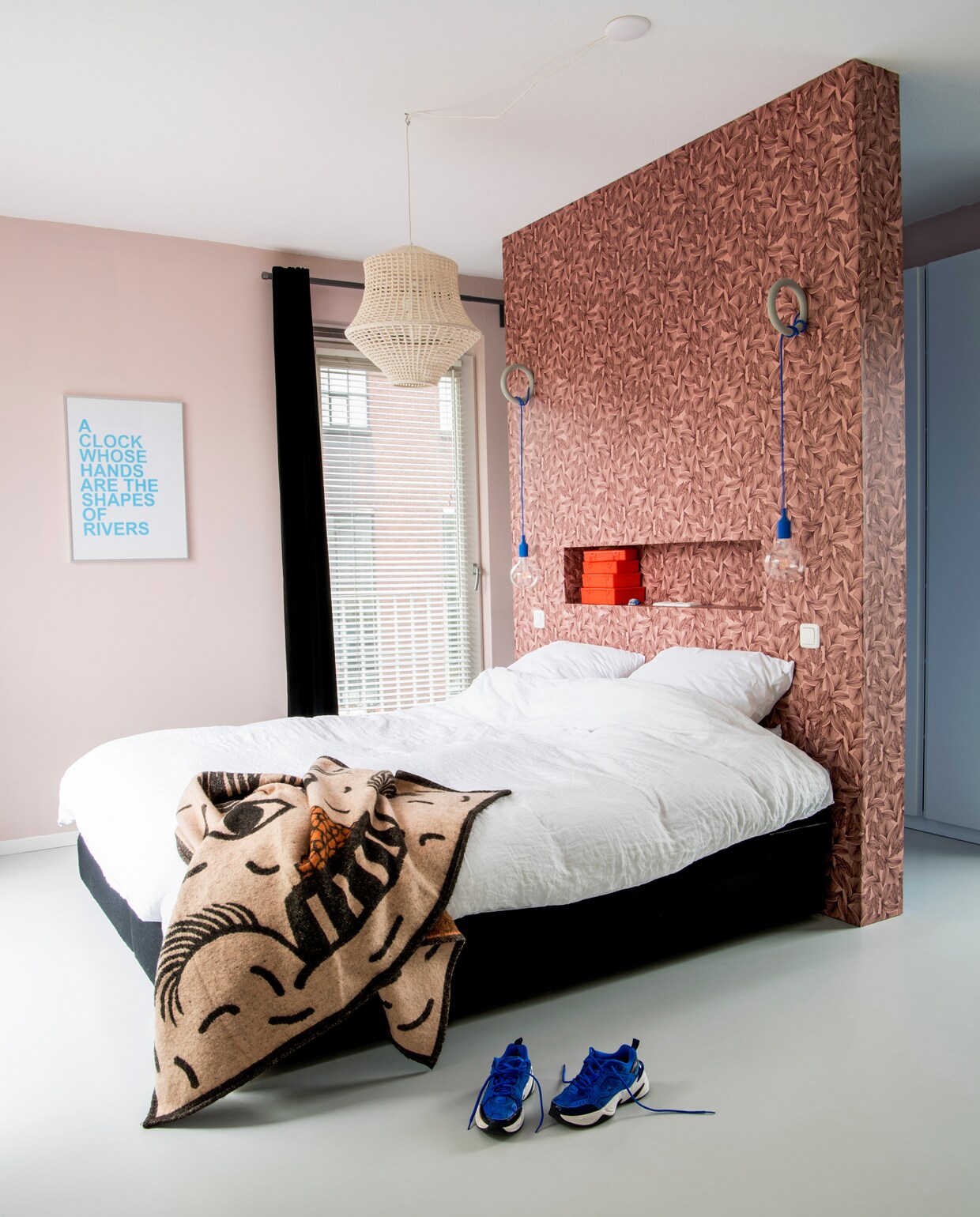 Marc maakte samen met de vader van Linda een roomdivider die behangen is met behang van Roomblush. Erop monteerde Marc twee Gym Hooks van Hay. Daaraan hangen lampen van Muuto. Witte hanglamp van Piet Hein Eek. Print aan de muur van David Horvitz. Deken Monki. Stapel oranje Japanse opbergdoosjes in nis, mudinmay.com. vtwonen 12 binnenkijken special 2019 | styling Kim de Groot | fotografie Anke Leunissen