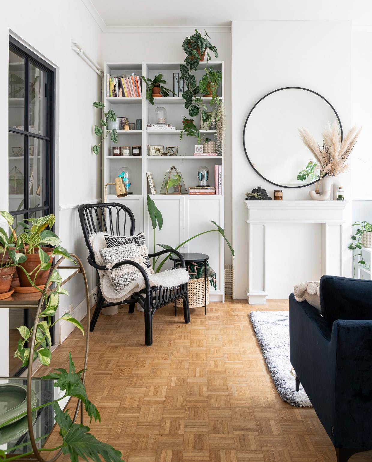 Schoorsteenmantel Maisons du Monde, kaars P.F. Candle Co, vaas H&amp;M Home, marmeren boekensteunen Wunderkammer, mosbol in water Juttu. Ronde spiegel Sissy-Boy. Zwarte rotan fauteuil, schapenvacht en kast Billy Ikea. Bijzettafel Sofacompany. In de kast: stolpen met vlinders Piet Moodshop, vintage stolpen Wunderkammer, kaarsen Soy Hive Candles. In de fauteuil kussens La Redoute en reissouvenir uit Bali. Overig onbekend. vtwonen 09-2022 | Fotografie Jonah Samyn | Tekst Katrien Depoorter
