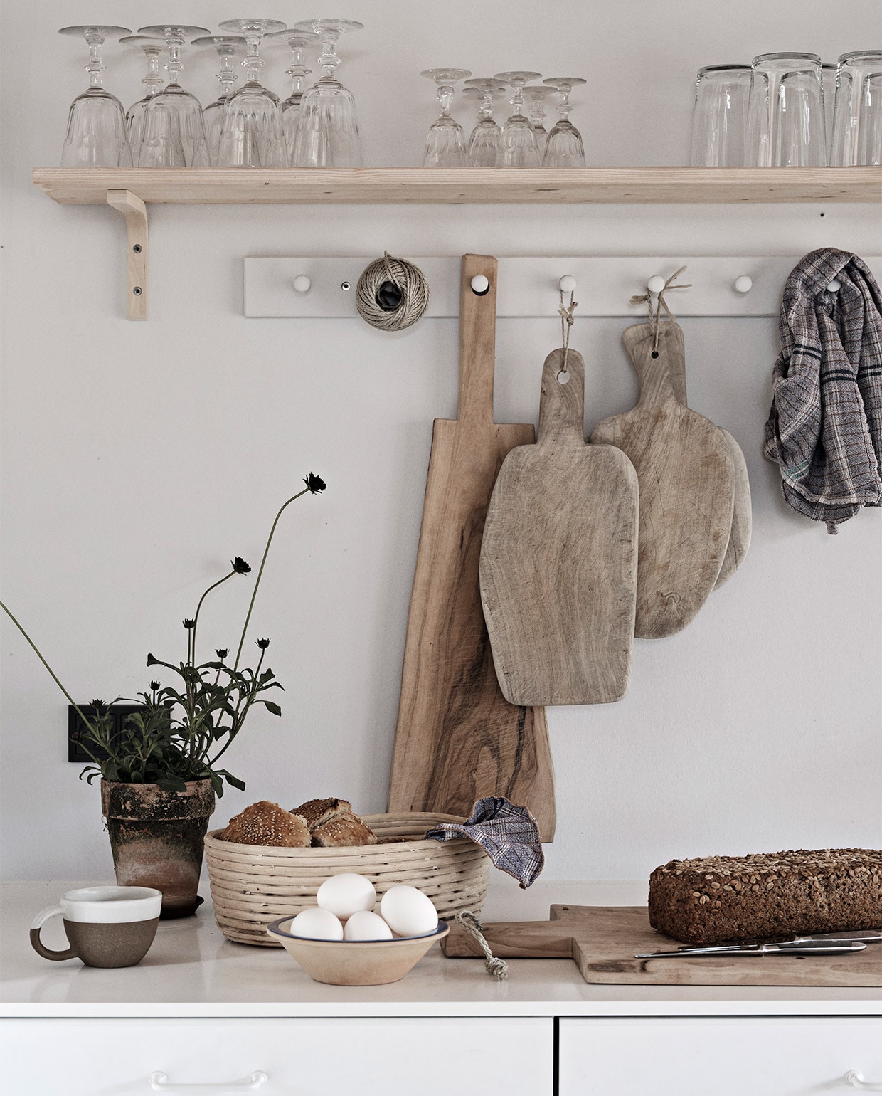 Keuken, wandrekken, glazen en hoge krijtwitte vaas Ikea. Eettafel en snijplanken Andrea Brugi. Metalen stoel Egon Eiermann, houten stoelen vintage. Vergelijkbare plafondlamp Lampion. Wandlampen Serge Mouille. Theeketel Le Creuset. Zilveren kan uit Griekenland, groen bord uit Marokko. Theedoek Aiayu. Overig onbekend. NEE | vtwonen binnenkijken special 03-2022 | productie Revolver, Living Inside | fotografie Mikkel Tjellesen | styling Marie Monrad Grounbøl