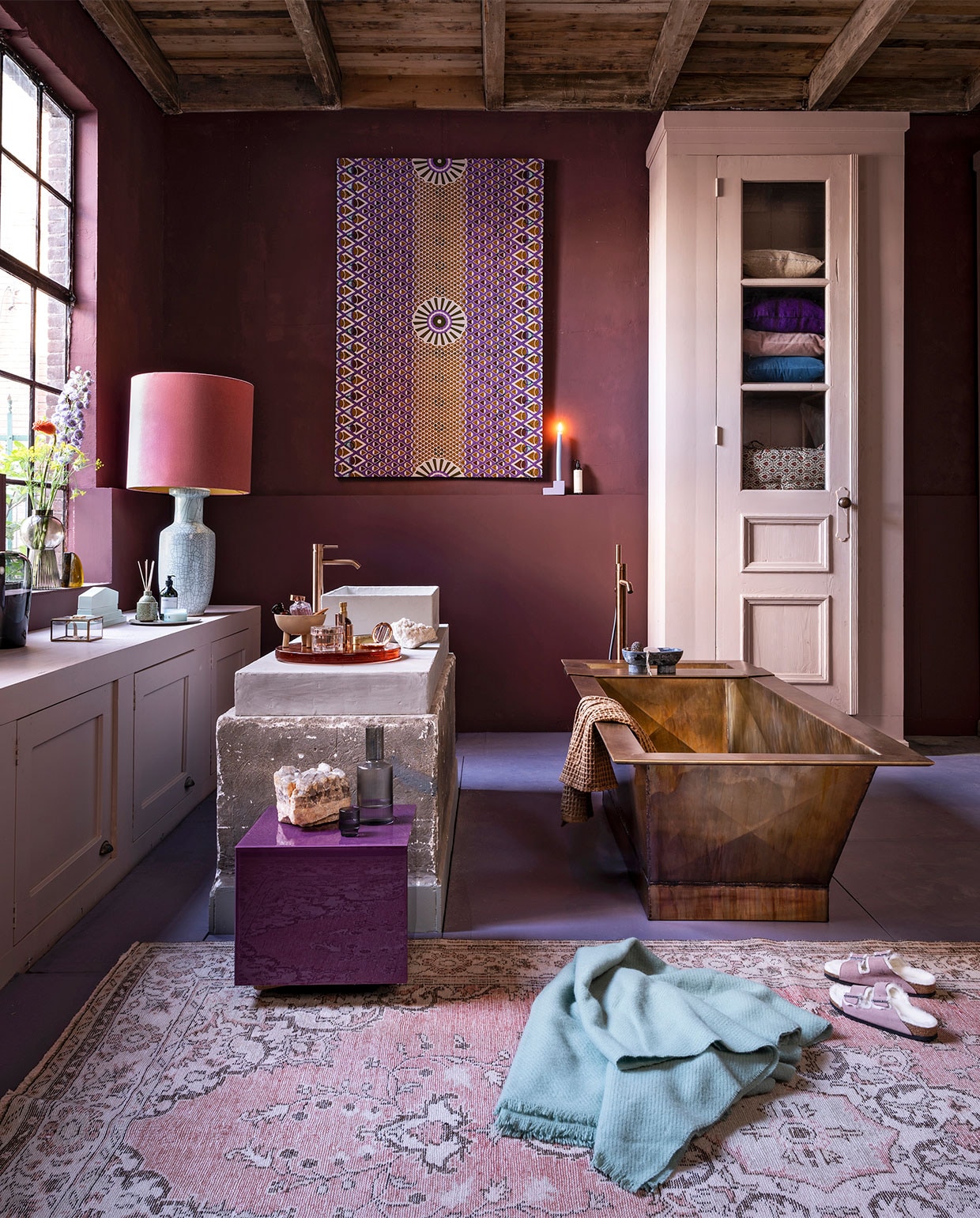 Badkamer aubergine , , Op de muur krijtverf Moorland per liter € 39,30, op de vloer lakverf Bohemian per liter € 61,40, verf op de kasten lakverf Old Rose per liter € 61,40 (pure-original.nl). Kasten, beide op maat gemaakt, prijs op aanvraag, wasbak prijs op aanvraag (com-anders.nl). Bad in gepatineerd messing, 2000x815x555 cm (lxbxh), prijs op aanvraag bij de koperslagerij (juliusballer.nl). Losstaande kraan in brons € 2050,-, wastafelkraanin brons € 525,- (jee-o.com). Plexiglazen tafel van HKliving € 195,- (vtwonen.nl). Doek van waxstof item nr. VL40850.365.02 vanaf € 54,95 (vlisco.com). Vloerkleed € 495,- (rozenkelim.nl). Lampenkap € 375,-, lampenvoet € 396,- (polspotten.nl). Glazen vaas van Menu € 69,95, glazen vaas op vensterbank van Bloomingville € 38,99, bord van HKliving € 17,50, waterkan van Ferm Living € 35,-, glazen van Ferm Living per 4 € 35,-, stenen zeepbakje van Ferm Living € 119,-, wafel handdoek van Ferm Living € 39,- (vtwonen.nl). Geel glazen object kwart cirkel van HKliving € 59,95 (deens.nl). Mintgroen keramisch object € 69,95, geurstokjes € 26,95, oranje glazen plateau € 259,- (hkliving.nl). Sieradendoosje € 19,-, kandelaar € 19,95, wollen deken van Hay € 75,- (eijerkamp.nl). Schaaltje op 3 poten € 30,- (101cph.com). Overig privébezit. vtwonen 10-2020 | styling Marianne Luning | fotografie Stan Koolen
