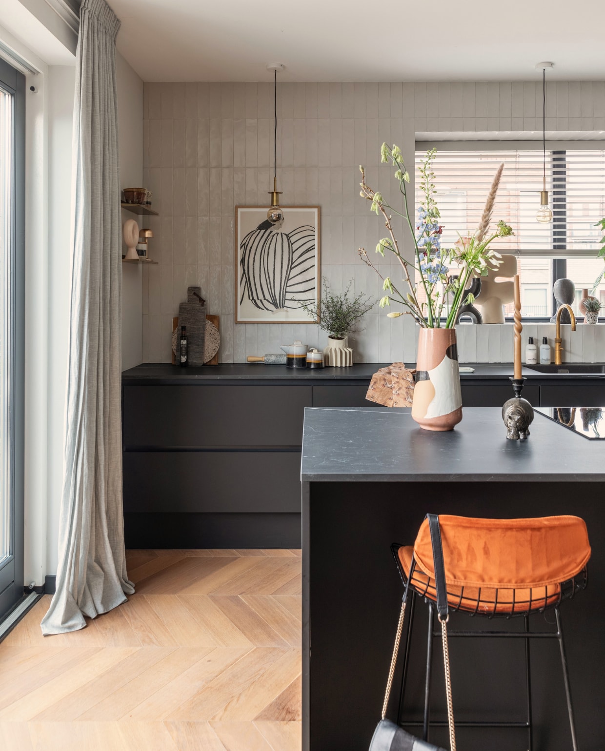 Keuken Bruynzeel Keukens, vloer Beboparket, wandtegels Tegeldeal, gordijnen Kwantum, kunst The Poster Club. Vaas op eiland, servies op aanrecht en barkruk HKliving. Messing wandplanken House Doctor. Oplaadbare messing lamp Humble Lights. Grote vaas in vensterbank 101Copenhagen. Snijplanken Brood en Plank, vaas met ribbels Floris Wubben. Hanglampen Gekaapt. Overig onbekend. vtwonen 09-2022 | Fotografie Margriet Hoekstra
