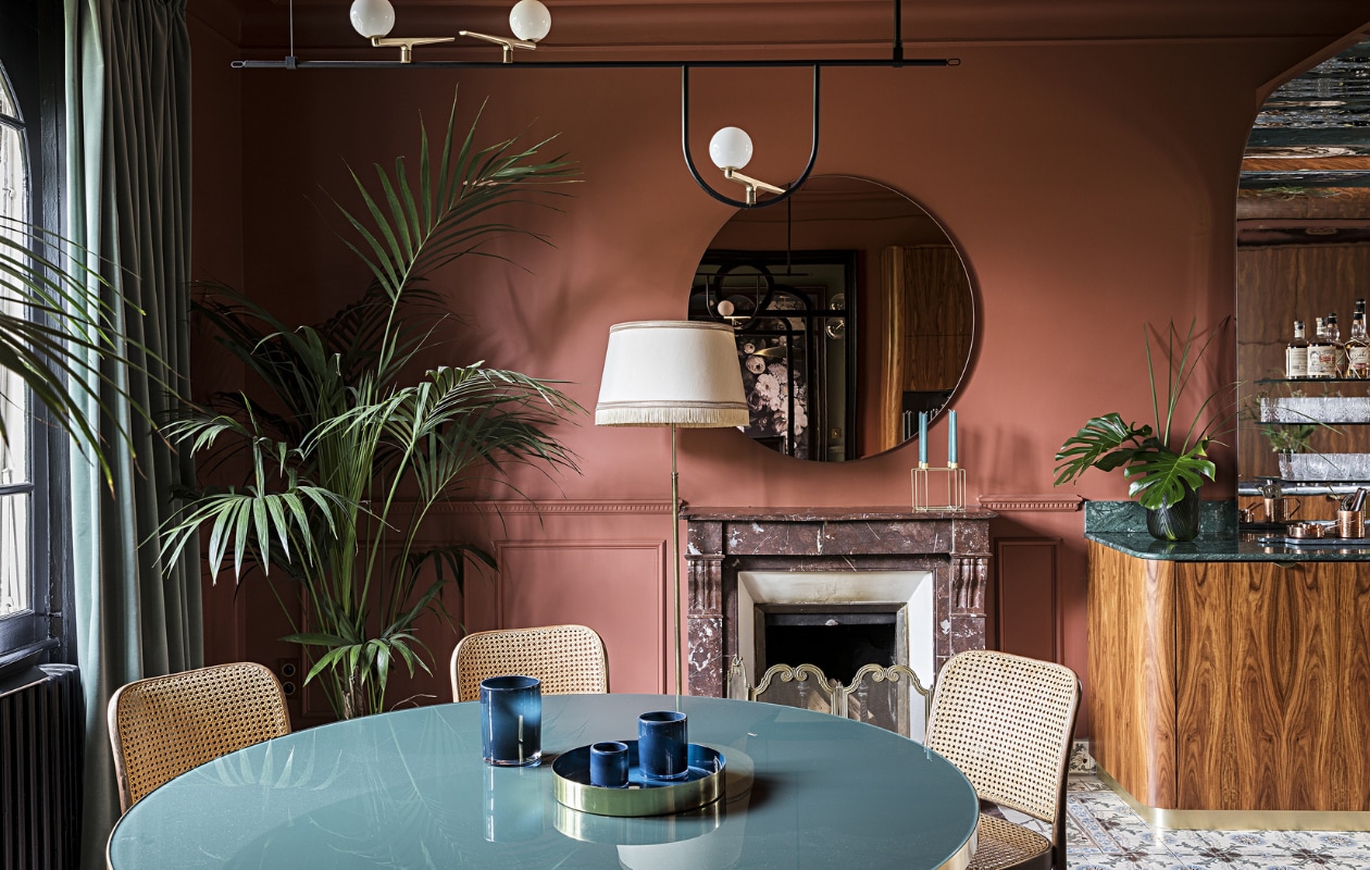 Muurverf Book Room Red van Farrow &amp; Ball. Tafel Gubi. Stoelen en vloerlamp tweedehands. Hanglamp Yanzi Artemide. Spiegel AYTM. De schouw en cementtegels zaten al in het huis. Overig onbekend. vtwonen special binnenkijken 2022-3 | Productie AC Scoffoni | Styling Marie-Maud Levron | Fotografie Yann Deret