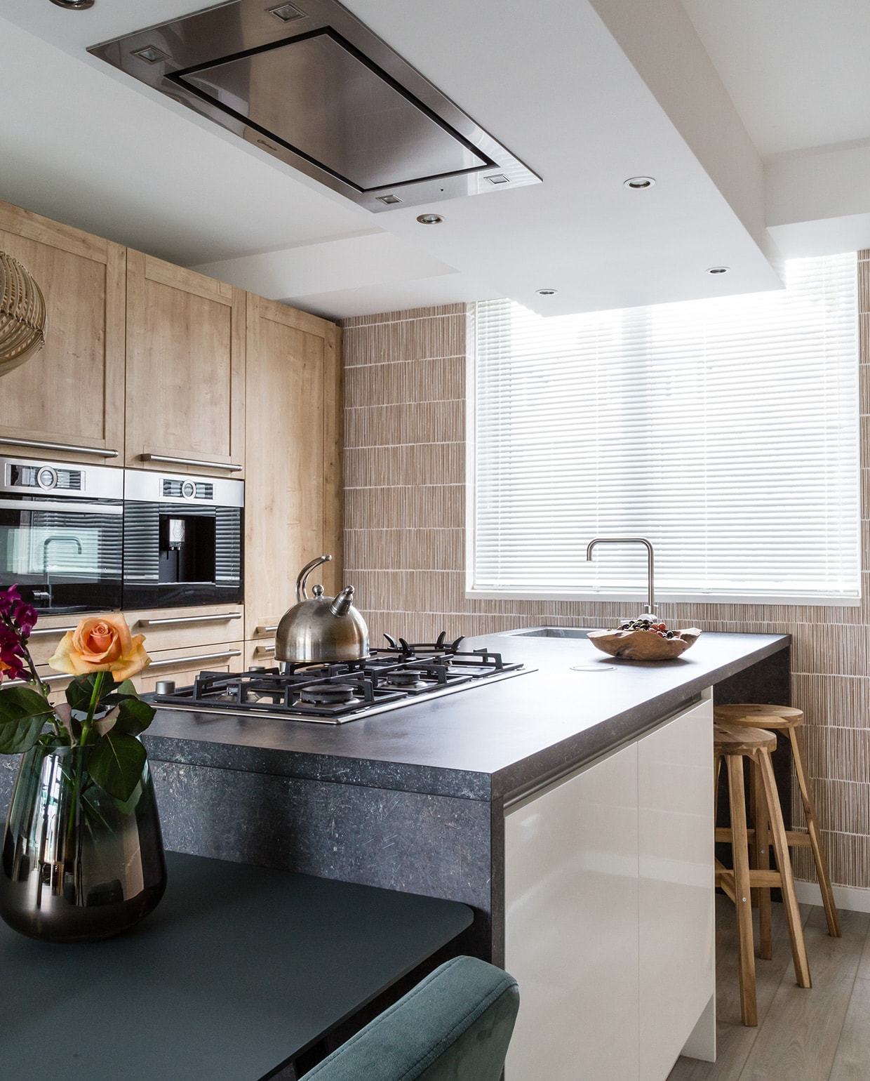 Muurverf 85% Hardsteen (flexa.nl). Behang Terra 391513, per rol € 69,95 (eijffinger.com). Hanglampen Kalahari van Good&amp;Mojo, per stuk € 205,-, eetkamertafel New Classic van Studio Henk € 1900,-, eetkamerstoelen Ode van Studio Henk, per stuk € 279,-, posters Floating Leaves van Moebe, per stuk € 26,95 (eijerkamp.nl). Vaas van pt € 36,95, kandelaar van Bloomingville € 33,- (vtwonen.nl). Keuken, kaars, waterkoker, bloemen, houten schaal privébezit. vtwonen weer verliefd op je huis | seizoen 11, aflevering 3 | styling Fietje Bruijn | fotografie Barbara Kieboom
