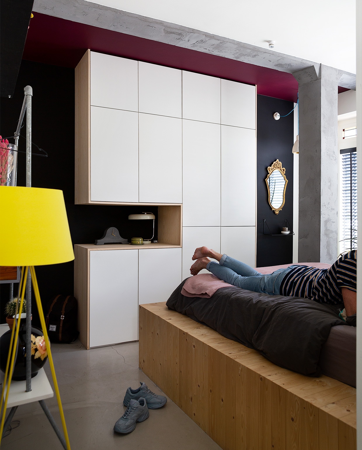 Bedombouw zelfgemaakt van grenen vloerdelen, beddengoed Walra, sprei H&amp;M Home, gele lamp Made, zwarte vaas Pols Potten, kledingrek, bloemenplank zelfgemaakt, hangers Hay, bloempot Intratuin. Hoge vaas kringloop, droogbloemen Bries aan Zee, glazen vaas Bloomon, ronde grijze vaas, klein vaasje, roze vaasje H&amp;M Home, flessen Casa, grote vaas Zara Home, lege drankflessen, pulpvaas Serax, buisje in stalen houder Sissy-Boy, geel vaasje Bloomingville, witte kan Ikea. Droogbloemen zelfgedroogd. Hanglamp Ferini Nieuwvliet. Kleur lichtgrijs op muur IG PS-1007 van Karwei, kleur donkergrijze streep Racebaan van Gamma, kleur wit op muur Ral 9010. Grijze bloempot Ikea, blauwe vaas Pols Potten, roze bloempot Mica Decorations, schilderijlijstje meegenomen uit Malawi. NEE  | vtwonen binnenkijken special 2021 | Fotografie Jansje Klazinga | Styling Roy Seen